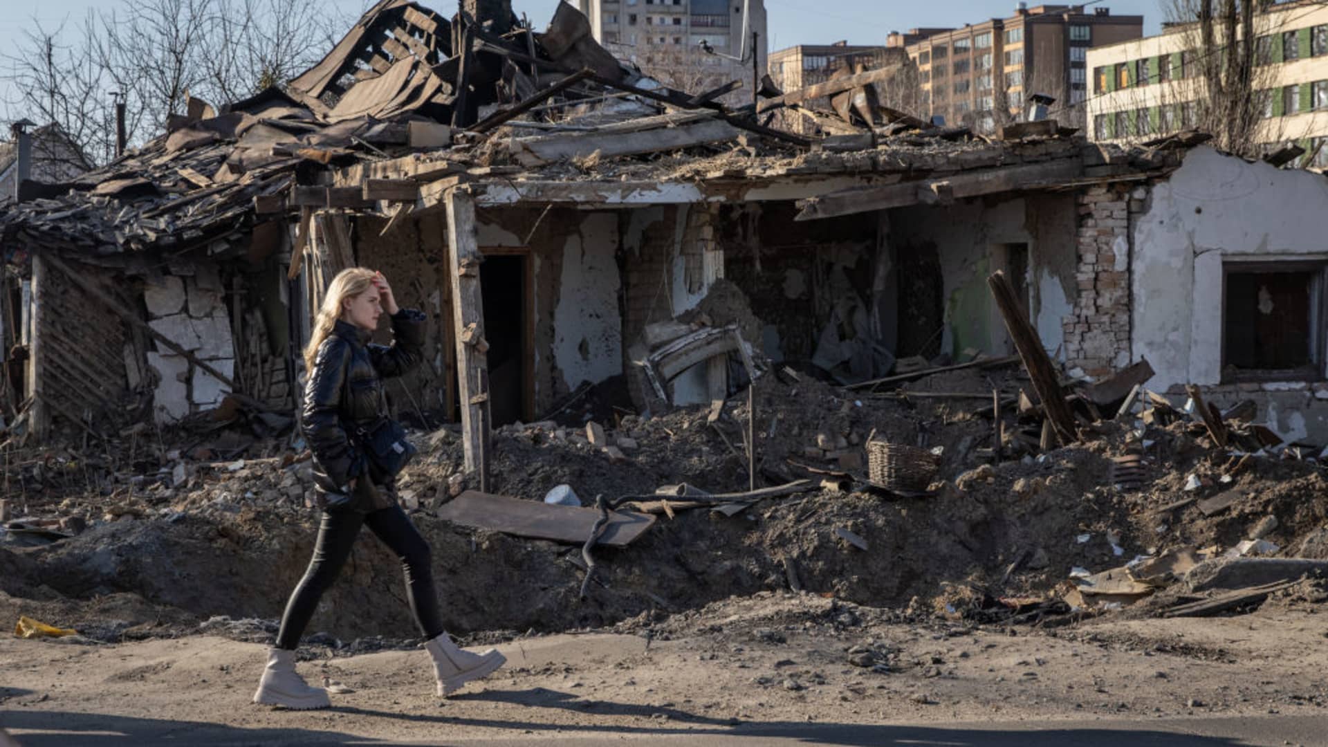 A woman walks past a rocket crater and a destroyed home destroyed that was struck in a recent Russian attack on March 20, 2022 in Zhytomyr, Ukraine.