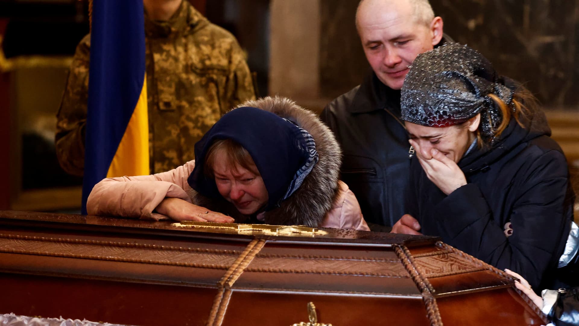 Olena, mother of Denys Snihur, 25, a border guard-turned-soldier, killed by Russian shelling in the northern town of Ovruch, and her daughter-in-law Carina mourn by his coffin during the memorial service at Saints Peter and Paul Garrison Church, in Lviv, Ukraine, March 21, 2022.