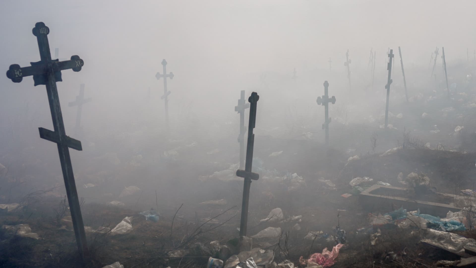 Crosses are pictured under smoke from a garbage in the cemetery of Mykolaiv, southern Ukraine, on March 21, 2022.