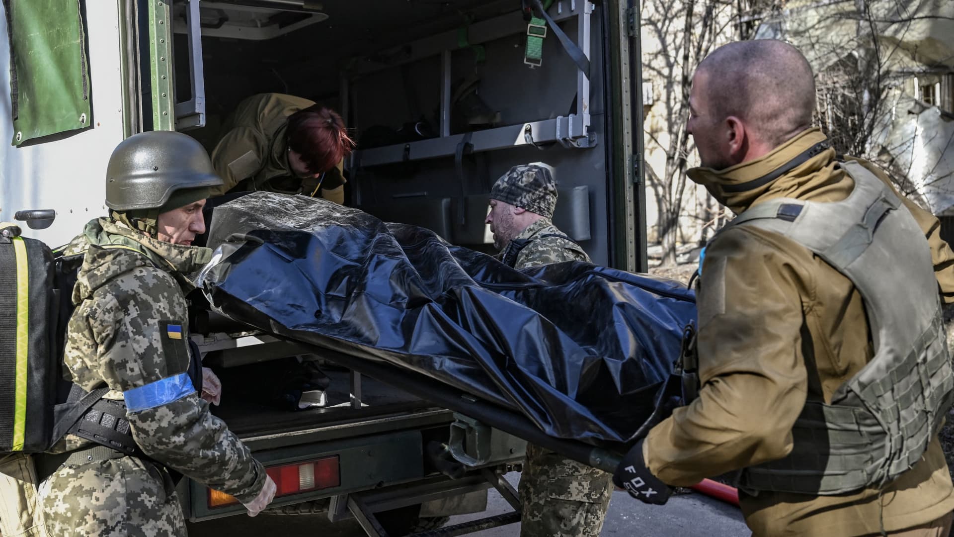 Military emergency service members remove the body of a dead Ukrainian serviceman in the area of a research institute, part of Ukraine's National Academy of Science, after a strike, in northwestern Kyiv, on March 22, 2022.
