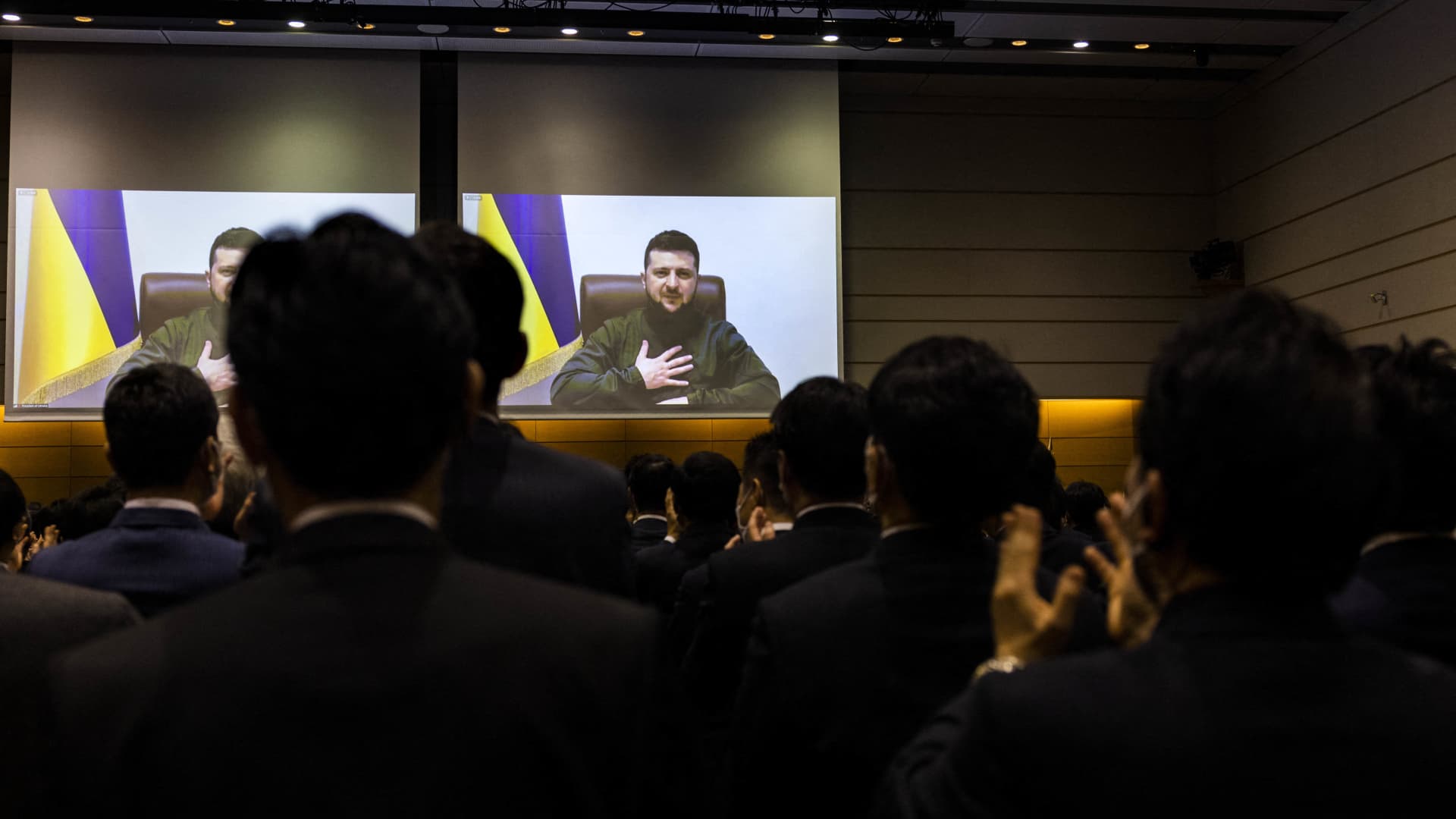 Members of Japan's lower house of parliament applaud as Ukrainian President Volodymyr Zelensky appears on screen via video link at the House of Representatives office building in Tokyo on March 23, 2022.