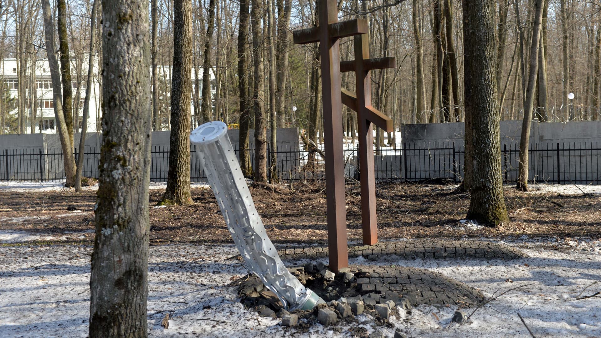 The internal components of a 300mm rocket which appears to contained cluster bombs launched from a BM-30 Smerch multiple rocket launcher are embedded in the ground next to graves after shelling near the Memorial to the Victims of Totalitarianism in a forest on the outskirts of Kharkiv on March 23, 2022.