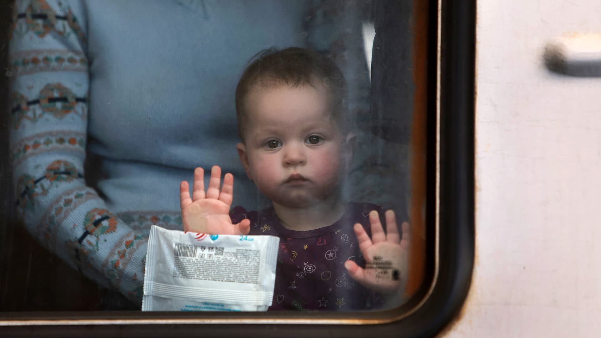 A young baby looks out as people leave on a train for Poland as they flee their home towns that are under Russian military attack on March 23, 2022 in Lviv, Ukraine.