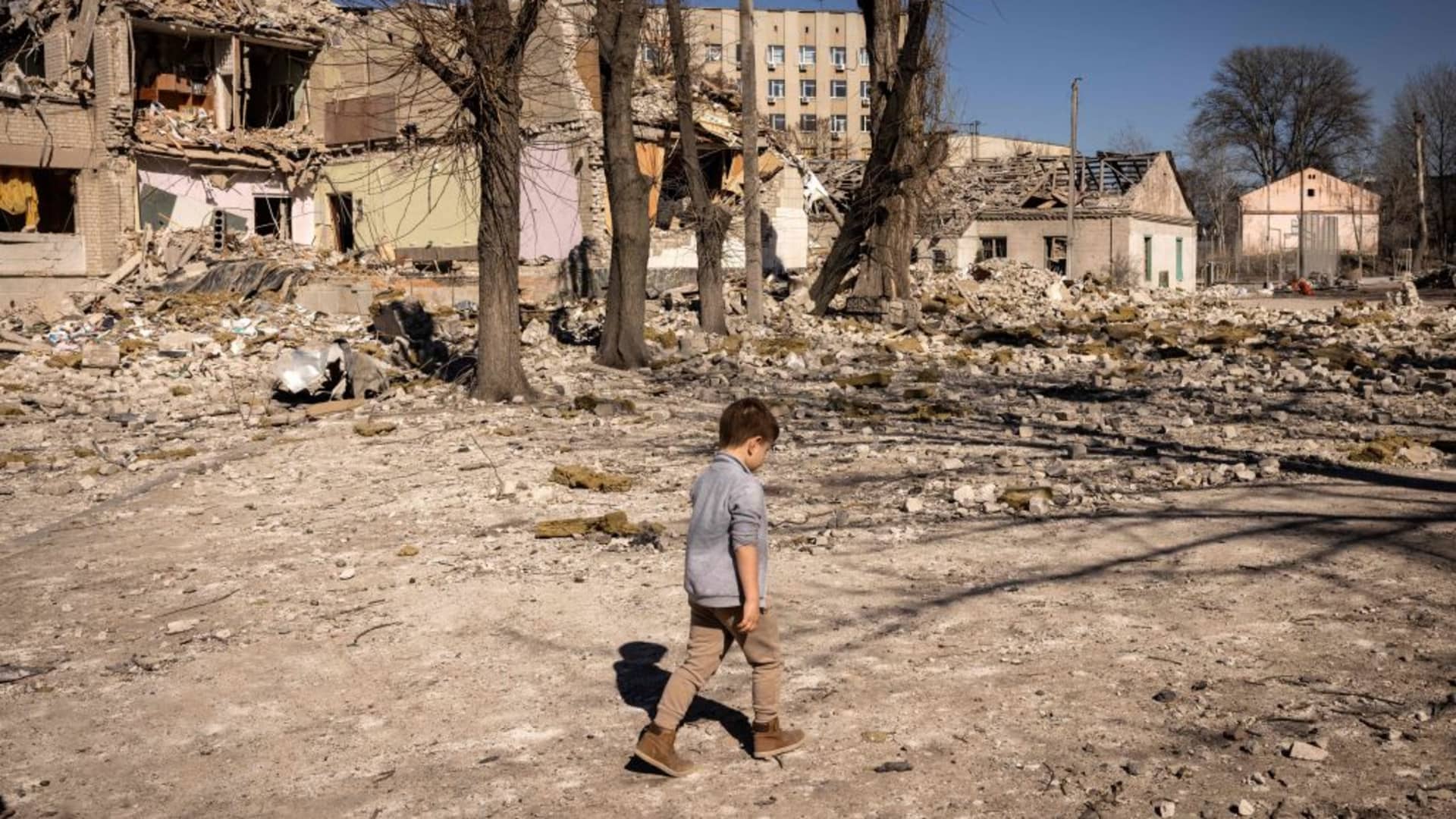 A children walks in front of a damaged school in the city of Zhytomyr, northern Ukraine, on March 23, 2022.