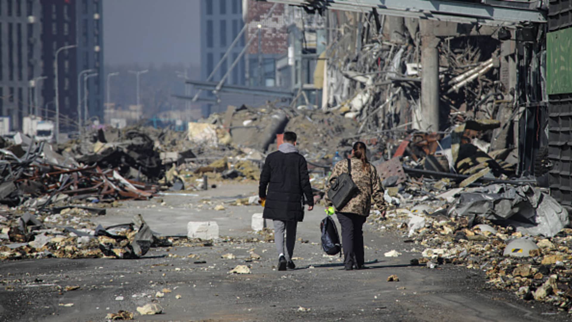 A man and a woman walk through rubble on the premises of a shopping mall ruined as a result of a missile strike carried out by the Russian troops in the Podilskyi district of Kyiv, capital of Ukraine