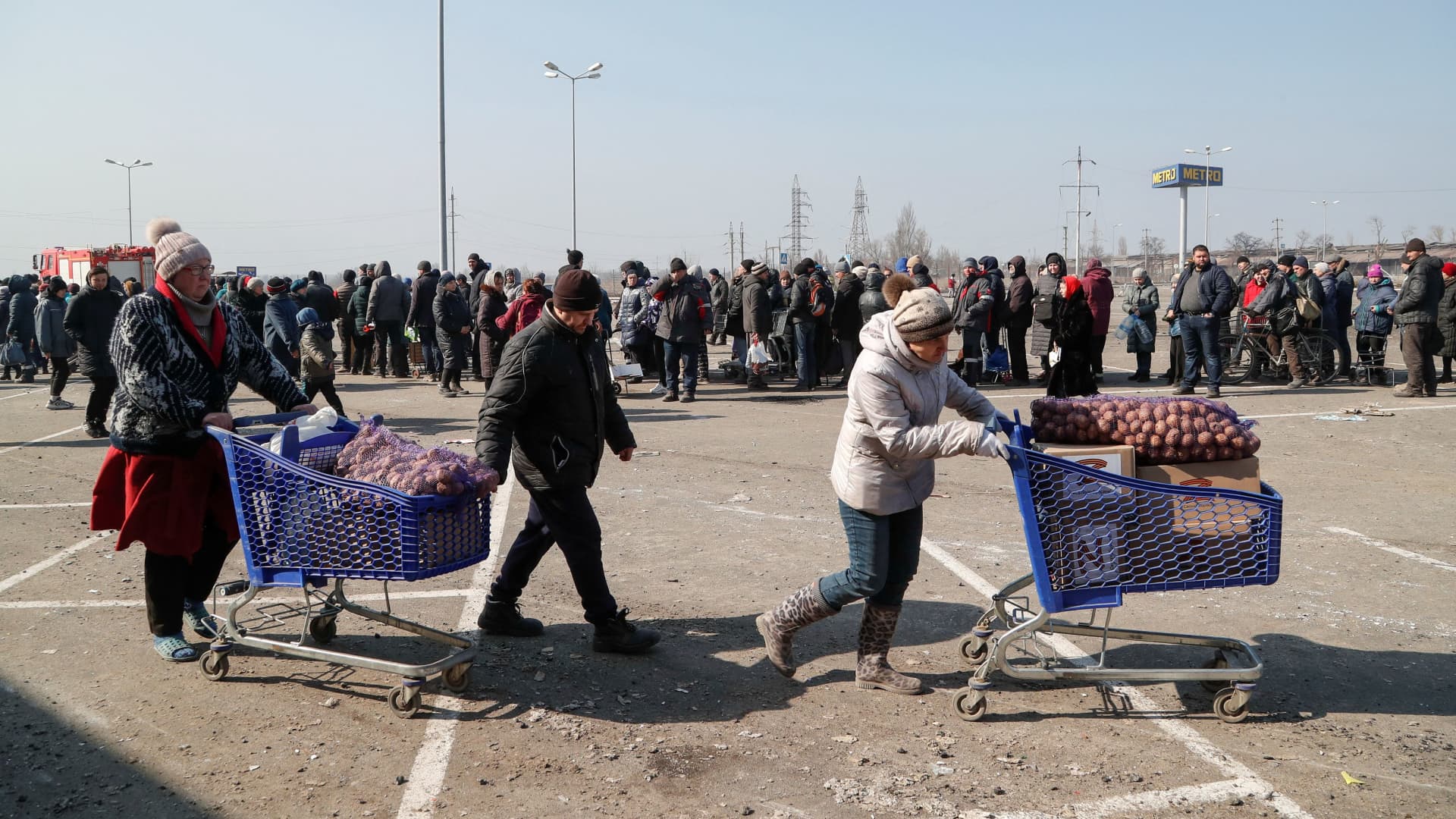People push carts after receiving humanitarian aid in a damaged store of wholesaler Metro in the besieged southern port city of Mariupol, Ukraine March 24, 2022.