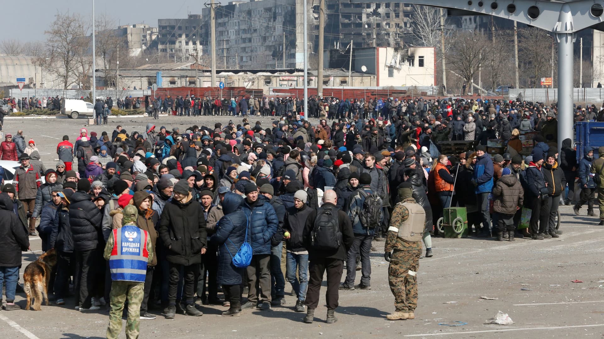 People stand in a long queue during the distribution of humanitarian aid near a damaged store of wholesaler Metro in the besieged southern port city of Mariupol, Ukraine March 24, 2022.