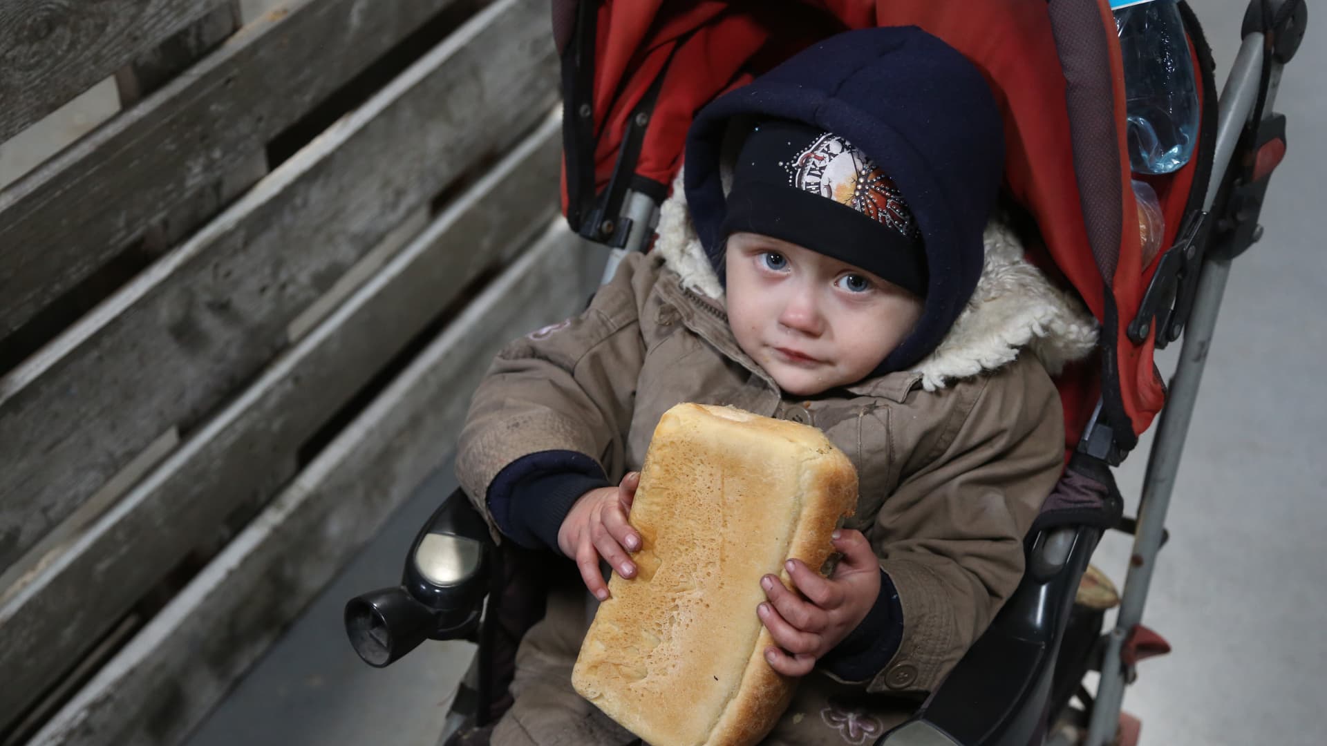 A child holds a bread as civilians are being evacuated along humanitarian corridors from the Ukrainian city of Mariupol under the control of Russian military and pro-Russian separatists, on March 24, 2022.