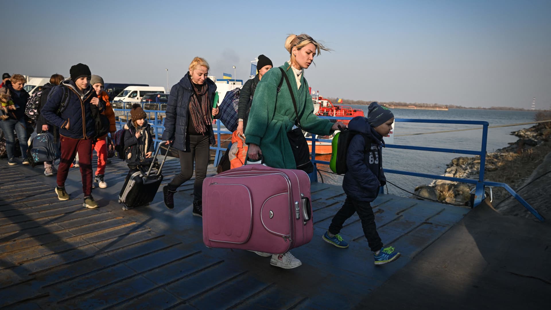 Refugees from Ukraine walk on the jetty after arriving by ferry at the Romanian-Ukrainian border point Isaccea-Orlivka on March 24, 2022.
