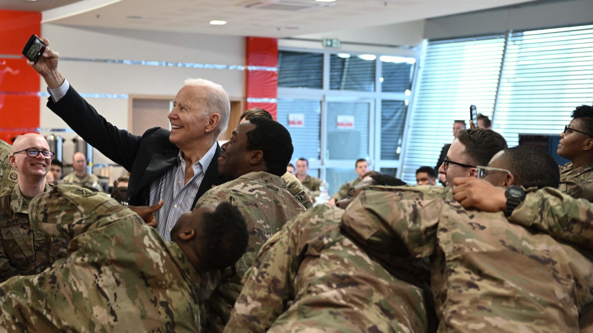 US President Joe Biden (L) takes a selfie photo as he meets service members from the 82nd Airborne Division, who are contributing alongside Polish Allies to deterrence on the Alliances Eastern Flank, in the city of Rzeszow in southeastern Poland, around 100 kilometres (62 miles) from the border with Ukraine, on March 25, 2022.