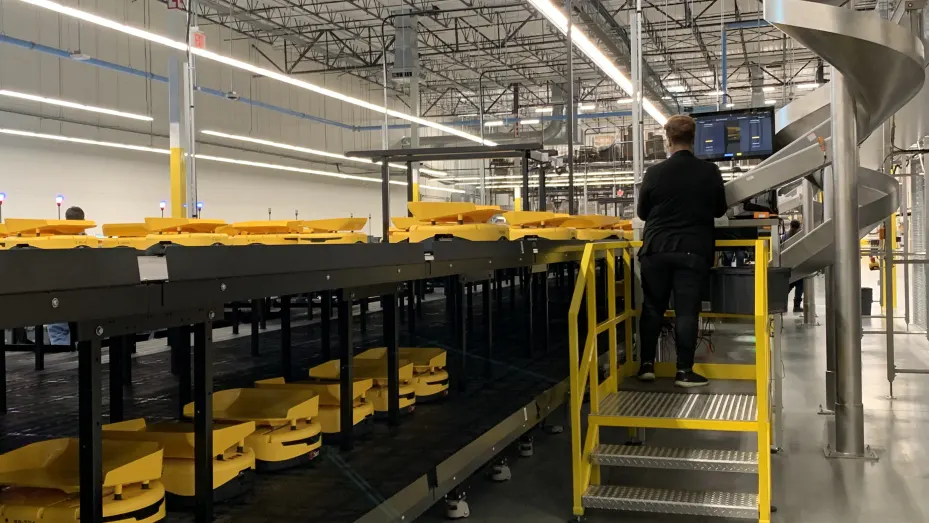 A worker places filled and packaged prescriptions on rolling robots at Walgreens' centralized facility in the Dallas area. The robots help sort the prescriptions and drop them into plastic totes that head to the same pharmacy location.