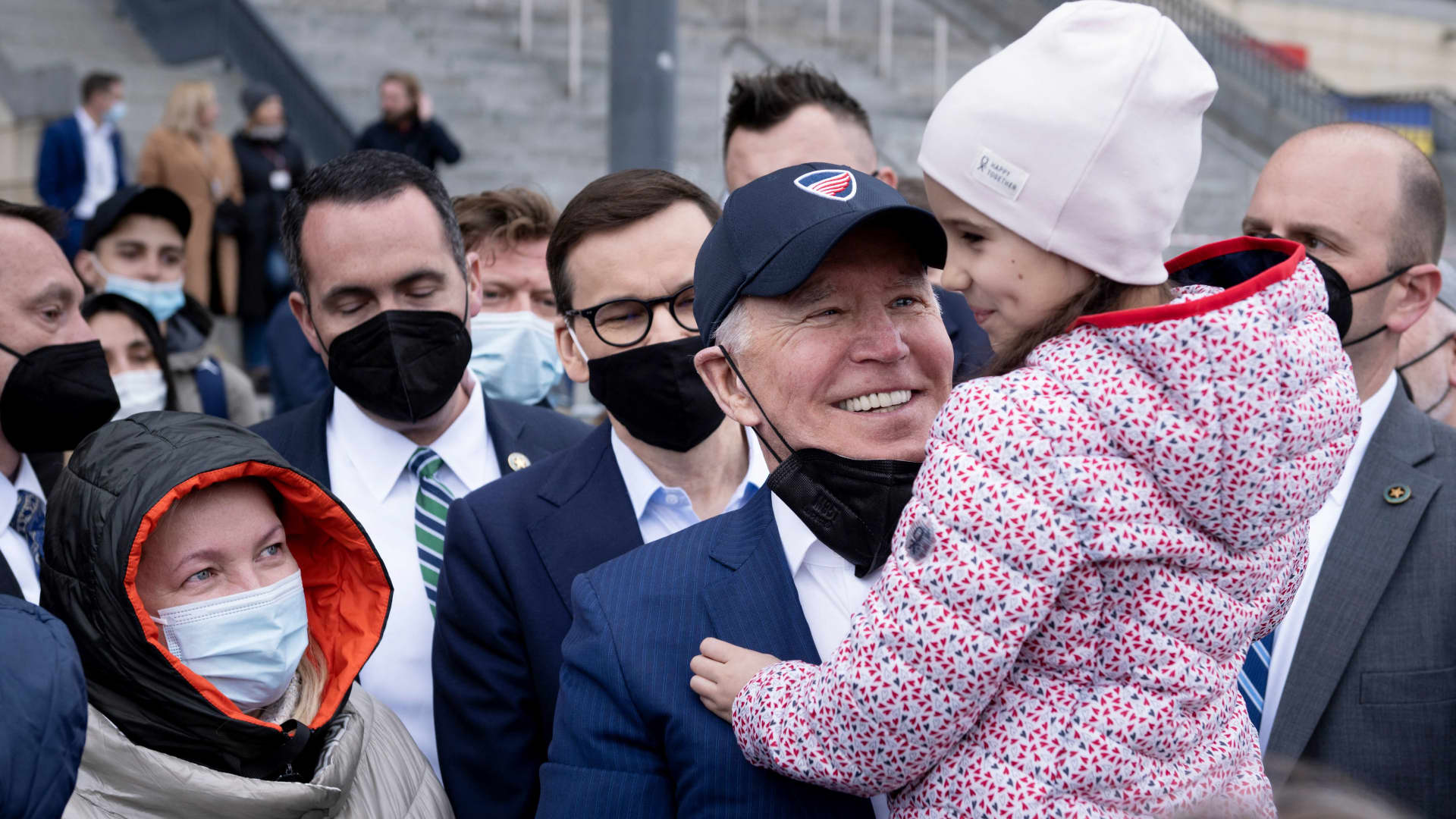 President Joe Biden holds a girl on his arm as he and Polish Prime Minister Mateusz Morawiecki meet with Ukrainian refugees at PGE Narodowy Stadium in Warsaw on March 26, 2022.