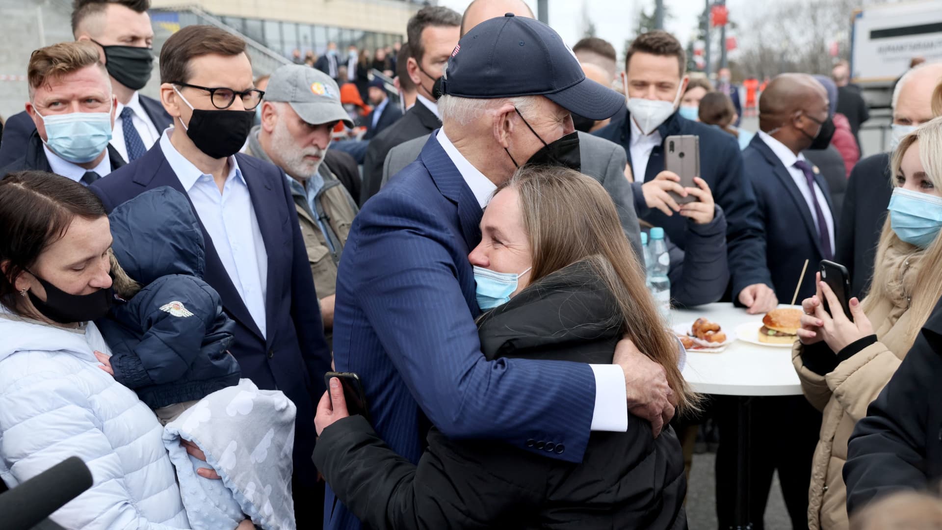 President Joe Biden, flanked by Mayor of Warsaw Rafal Trzaskowski and Polish Prime Minister Mateusz Morawiecki, hugs a woman as he visits Ukrainian refugees at the PGE National Stadium, in Warsaw, Poland March 26, 2022.
