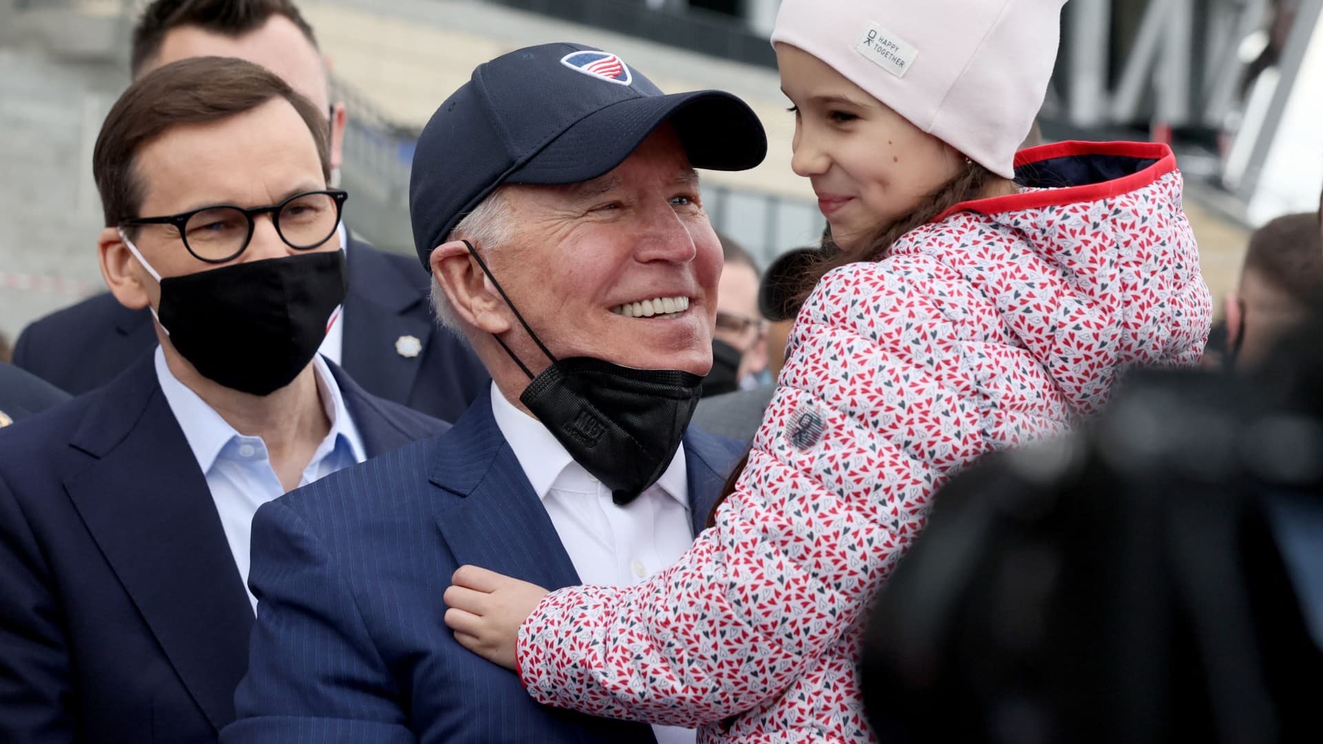 U.S. President Joe Biden, flanked by Polish Prime MInister Mateusz Morawiecki, holds a child as he visits Ukrainian refugees at the PGE National Stadium, in Warsaw, Poland March 26, 2022.
