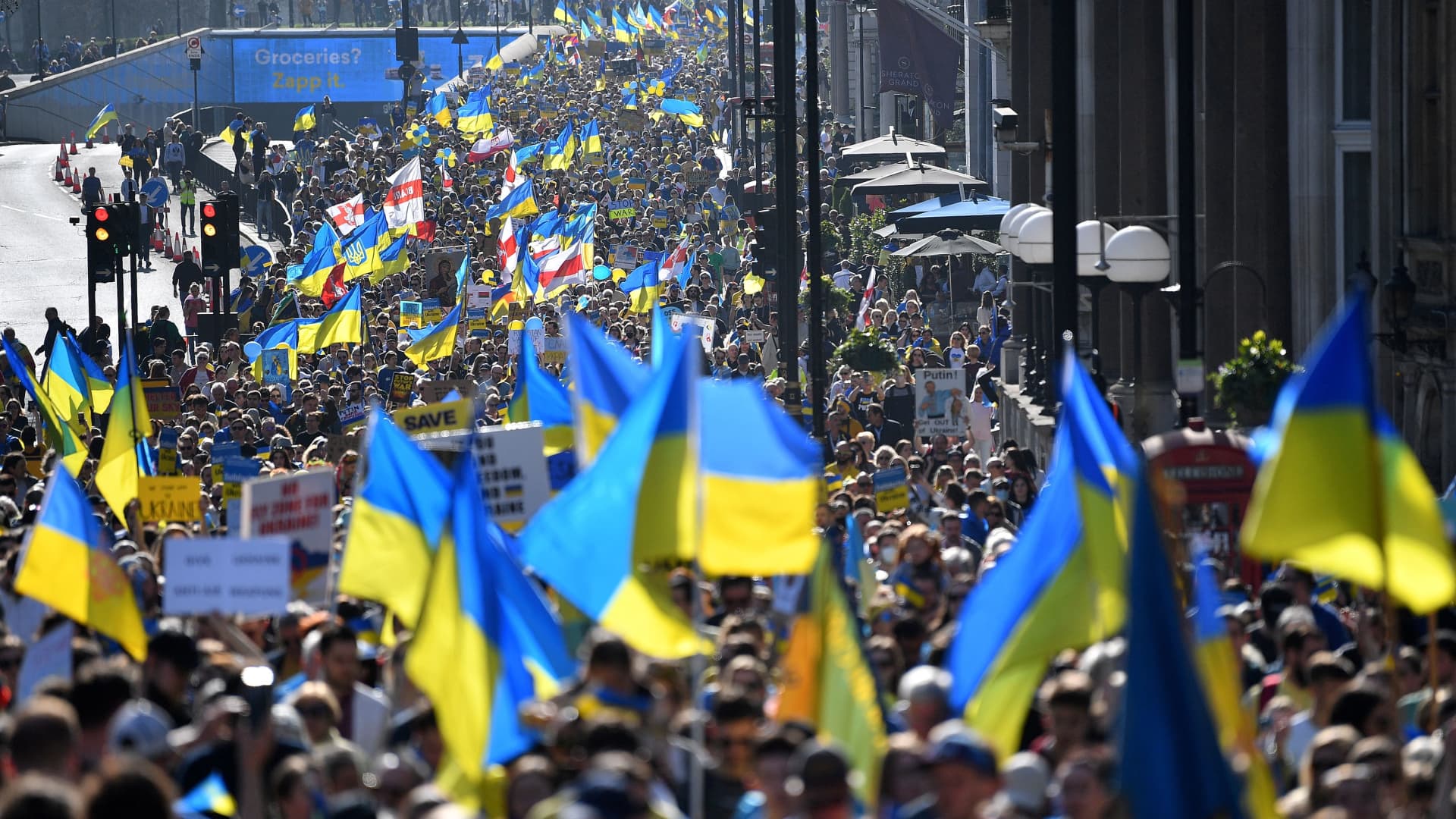 Demonstrators wave Ukrainian national flags during a 'London stands with Ukraine' protest march and vigil, in central London, on March 26, 2022 to send a unified message of support to the Ukrainian people. 