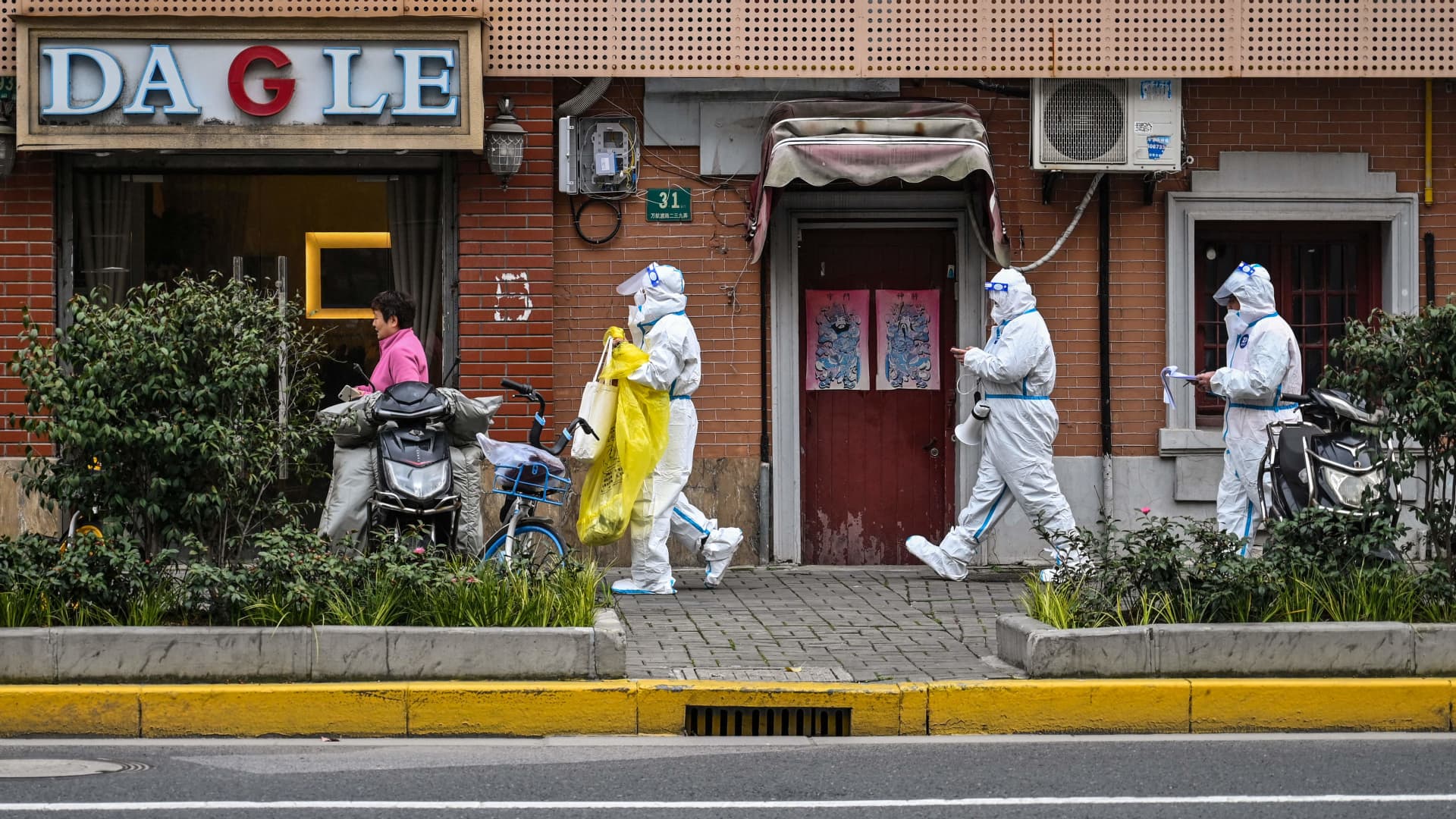 Health workers wearing protective gear as a measure against the Covid-19 coronavirus walk down a street in Jing'an district in Shanghai on March 26, 2022.