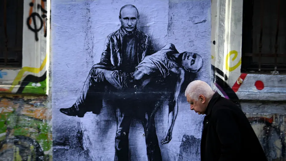 A resident walks past mural painting by Bulgarian artist Stanislav Belovski depicting Russian President Vladimir Putin holding his own body in Sofia, on March 15, 2022.