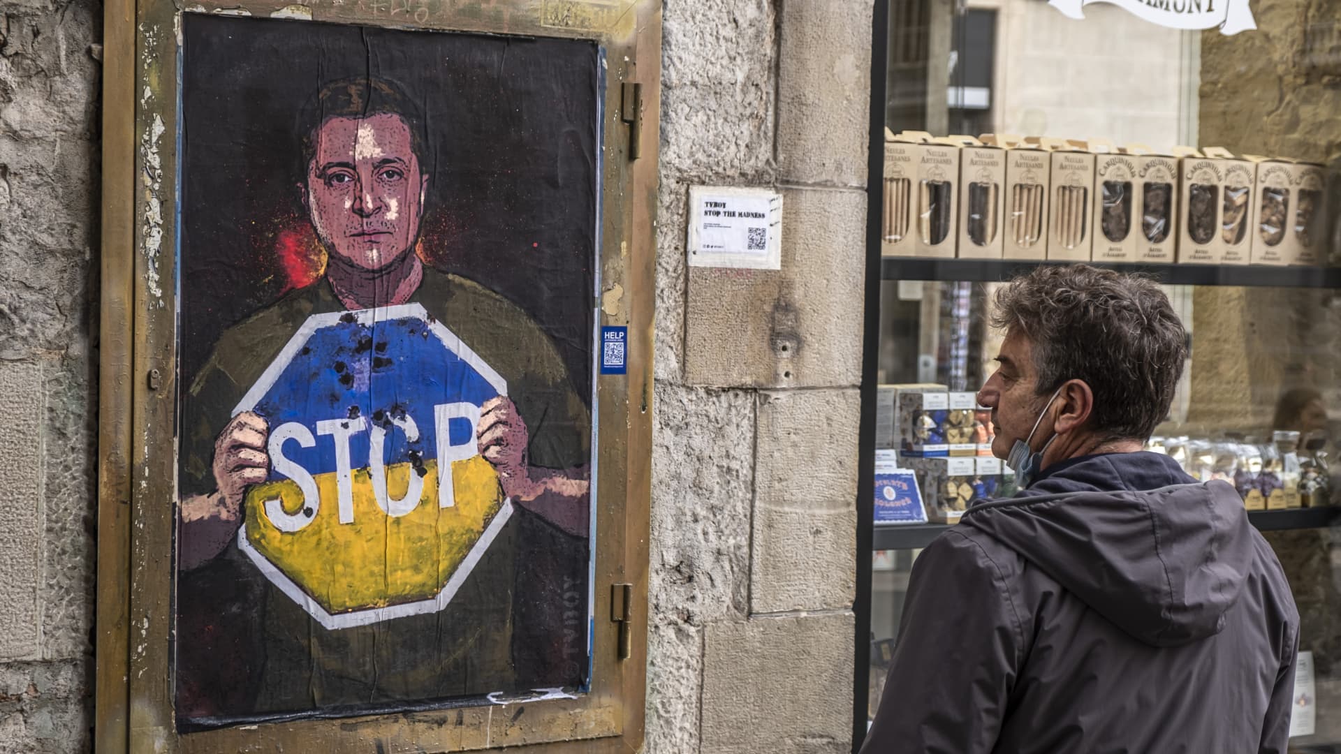 A passer-by is seen observing the graphic representation of Ukraine's president Zelensky calling for an end to the Russian invasion is seen in Plaza de Sant Jaume.