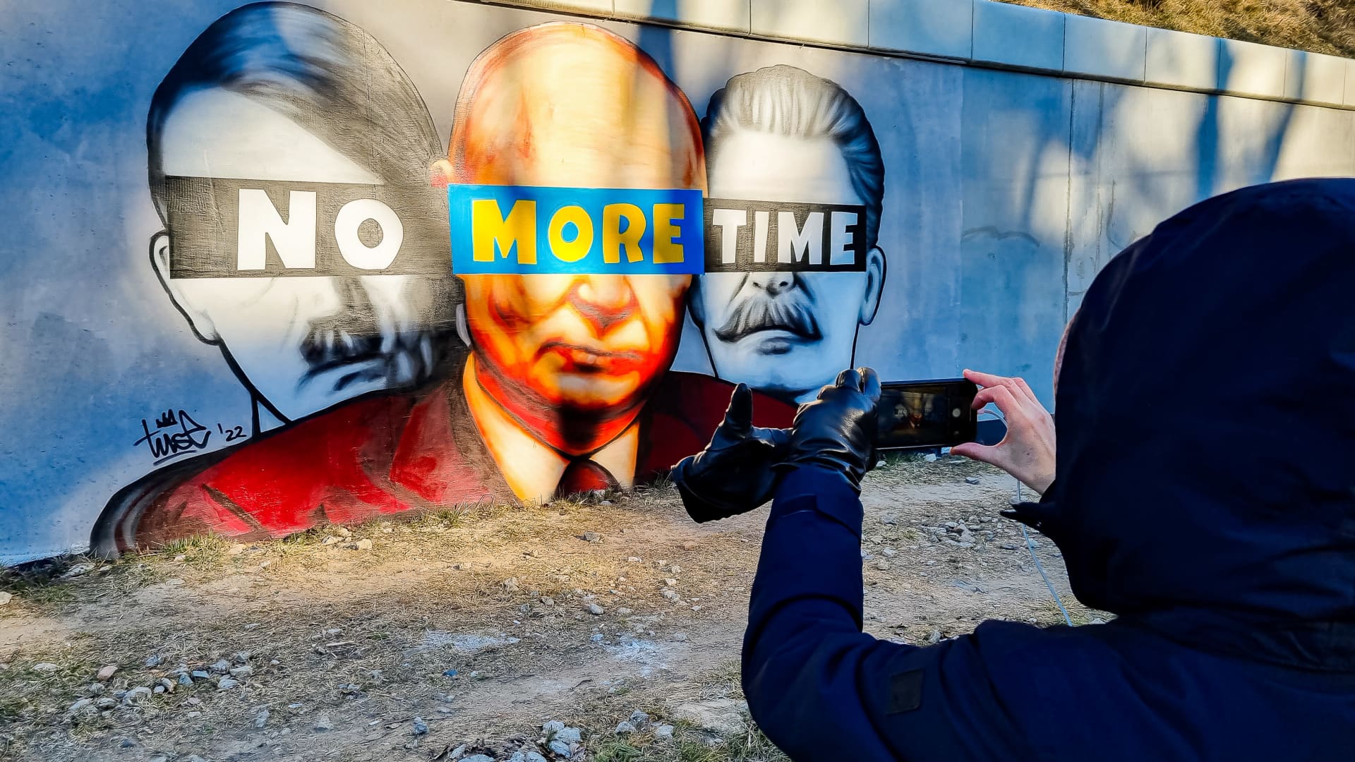 A mural of Putin, Hitler, and Stalin with a slogan 