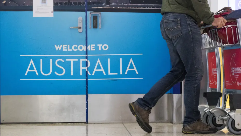 A traveler walks past a sign at the arrival hall at the international terminal of Sydney Airport in Sydney, Australia, on Monday, Feb. 21, 2022. Australia reopened its international borders to double-vaccinated visitors today, following almost two years of strict travel bans introduced to stem the spread of Covid-19.