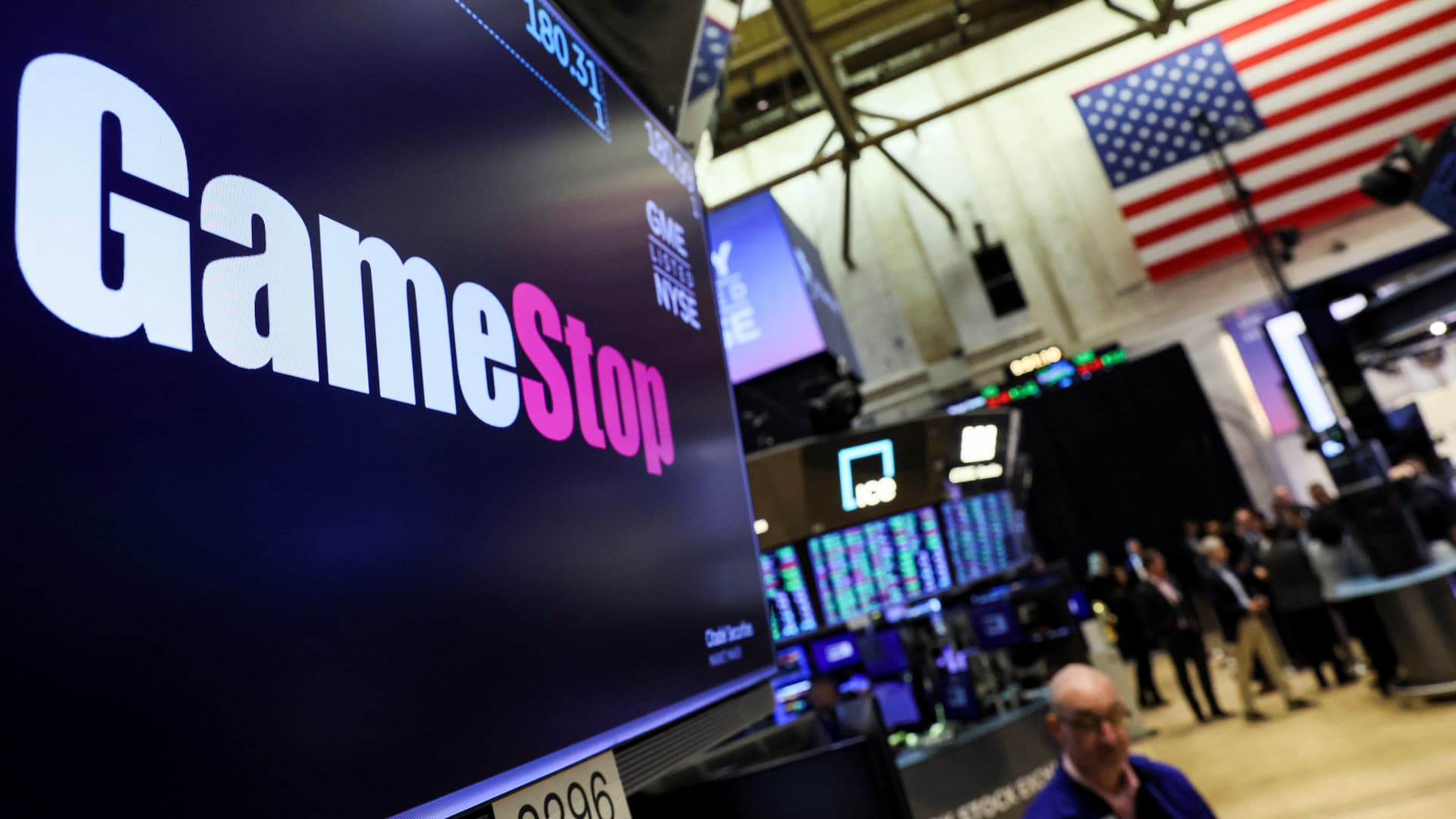 A screen displays the logo and trading information for GameStop on the floor of the New York Stock Exchange on March 29, 2022.