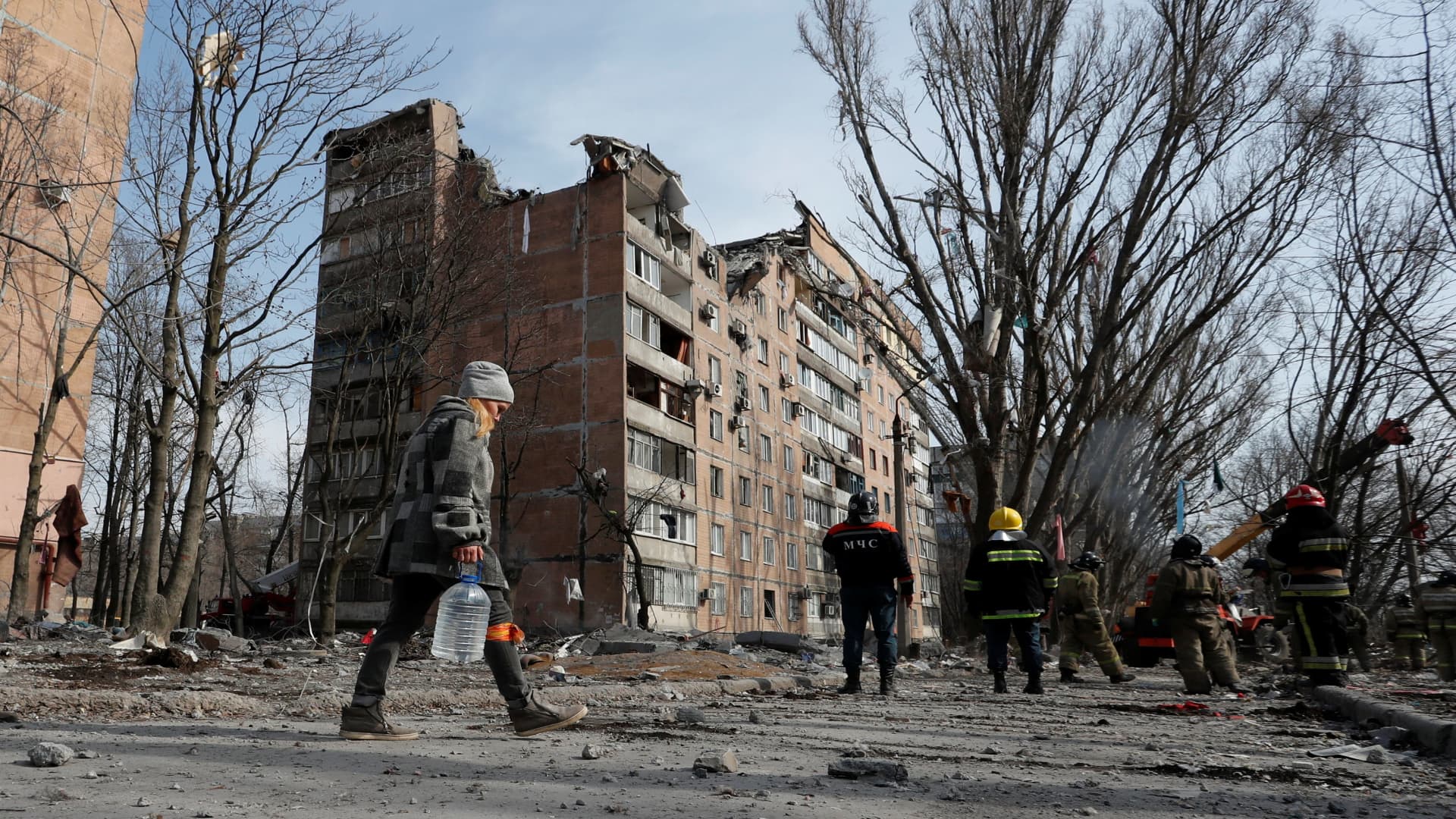 A woman carries a bottle of water as emergency specialists work at a residential building damaged by shelling during Ukraine-Russia conflict in the separatist-controlled city of Donetsk, Ukraine March 30, 2022.