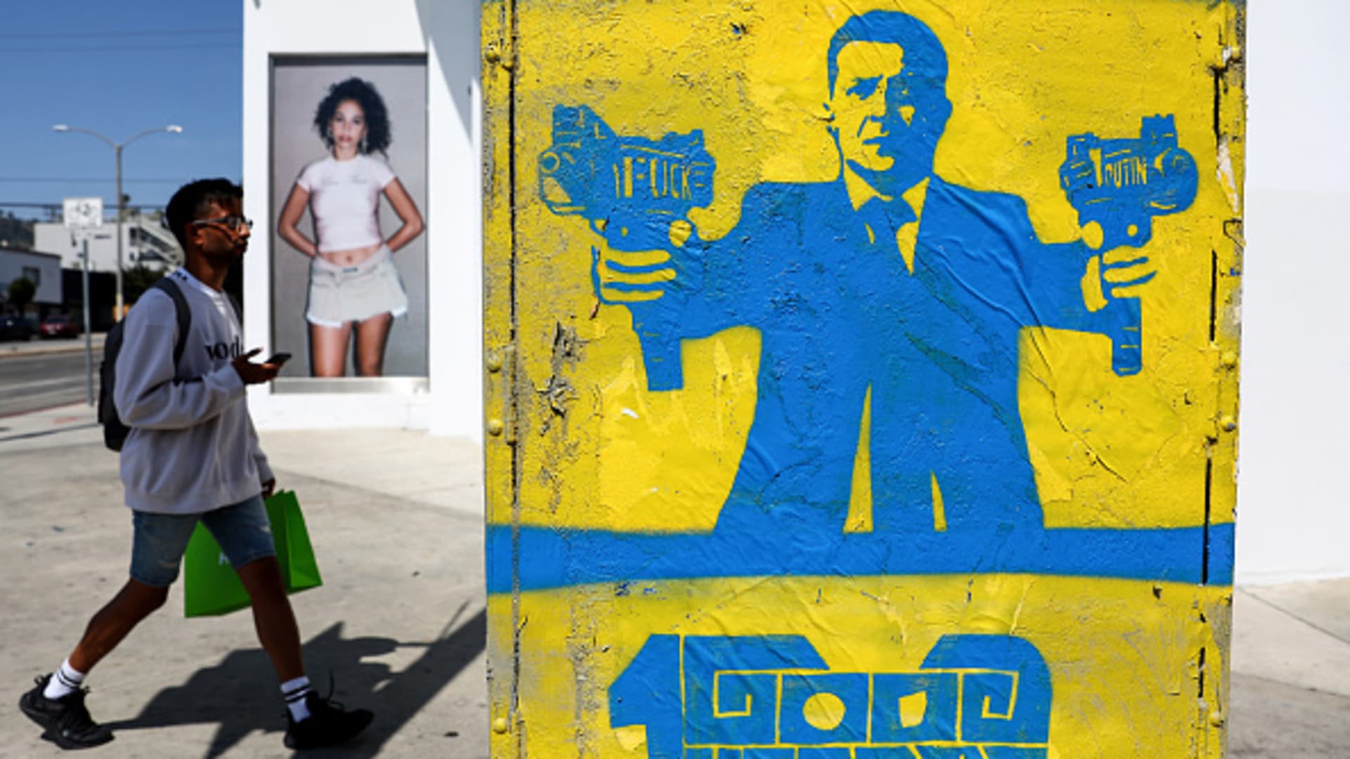A street stencil by artist 1GoodHombre depicts Ukrainian President Volodymyr Zelenskyy gripping submachine guns as a person walks past on Melrose Avenue on March 30, 2022 in Los Angeles, California.