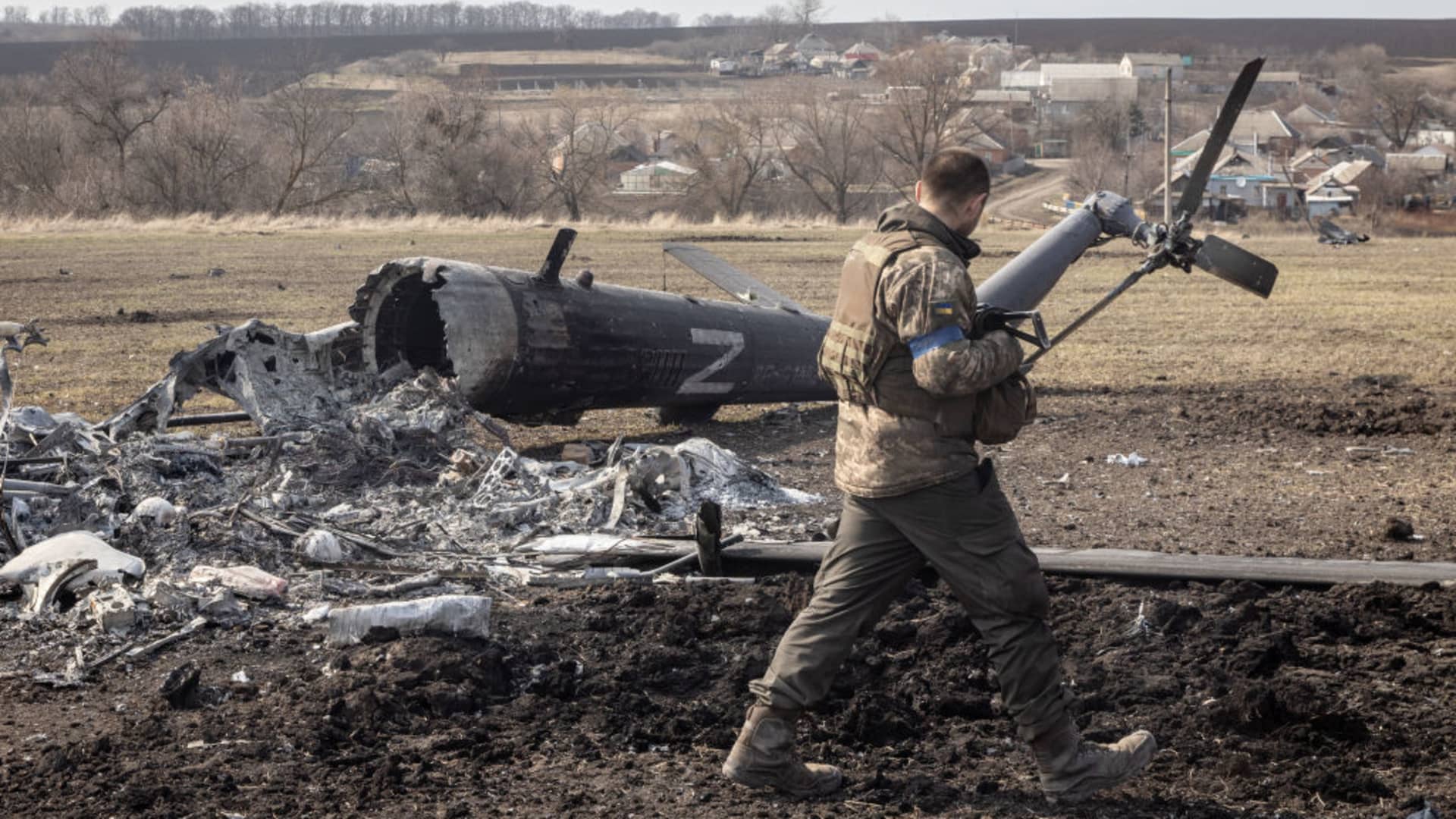 A Ukrainian soldier walks past the remains of a downed Russian helicopter near Kharkiv on March 31, 2022.