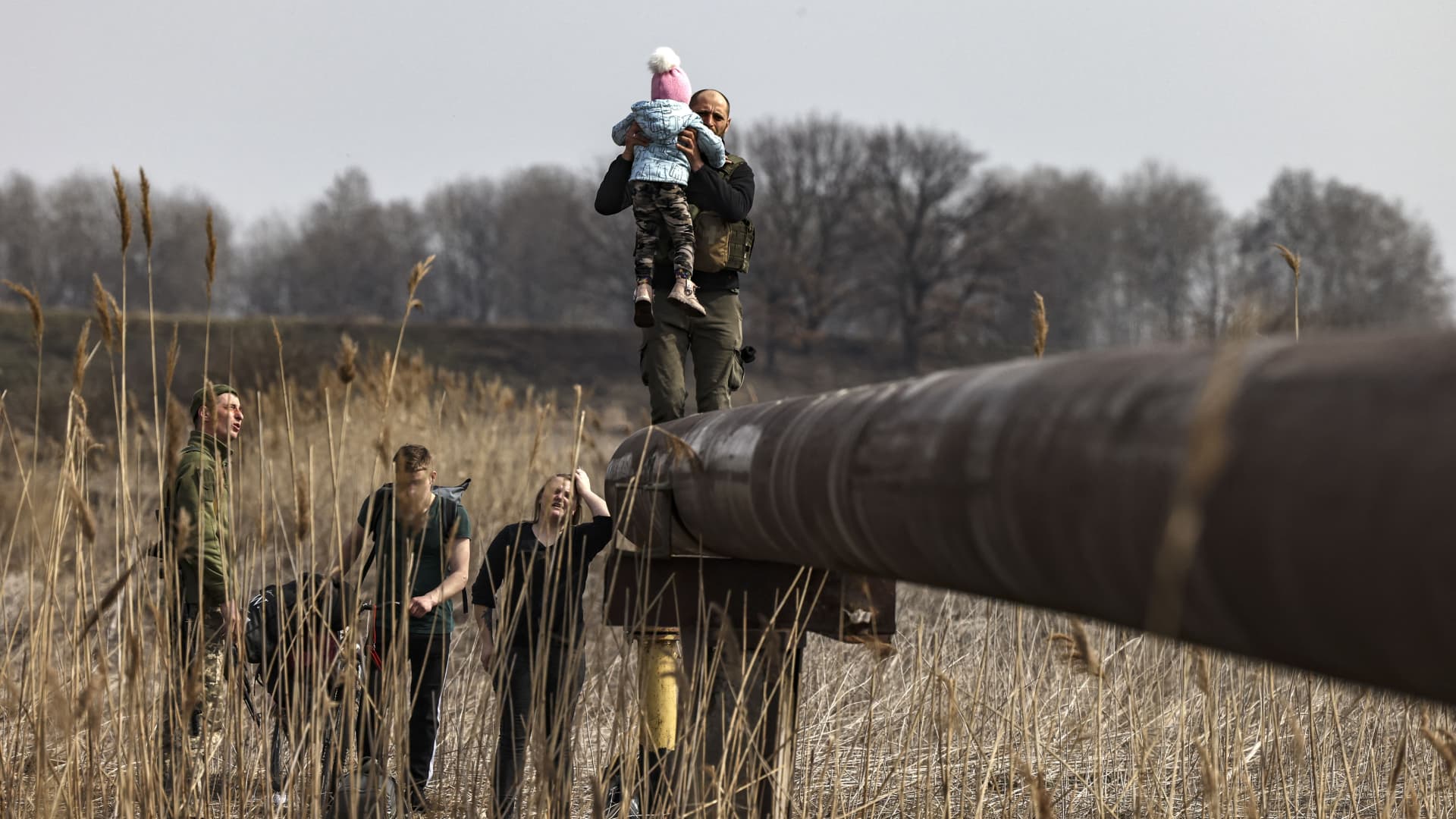 Ukrainian displaced Karina Tkachenko carries her baby after he was helped by Ukrainian servicemen to cross a river, on the outskirts of Kyiv, on March 31, 2022. 
