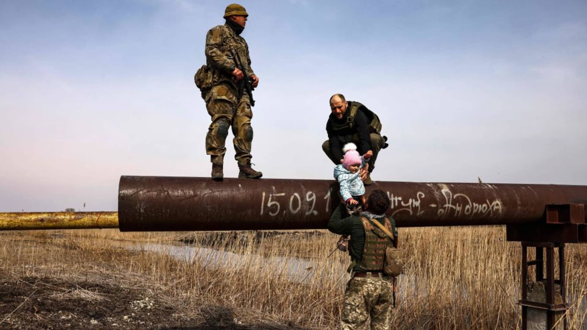 Ukrainian displaced Karina Tkachenko carries her baby after he was helped by Ukrainian servicemen to cross a river, on the outskirts of Kyiv, on March 31, 2022. - Russian forces are repositioning in Ukraine to strengthen their offensive on the Donbass, Nato said March 31, 2022, on the 36th day of the Russian-Ukrainian conflict, as shelling continues in Kharkiv (north) and Mariupol (south). (Photo by RONALDO SCHEMIDT / AFP) (Photo by RONALDO SCHEMIDT/AFP via Getty Images)