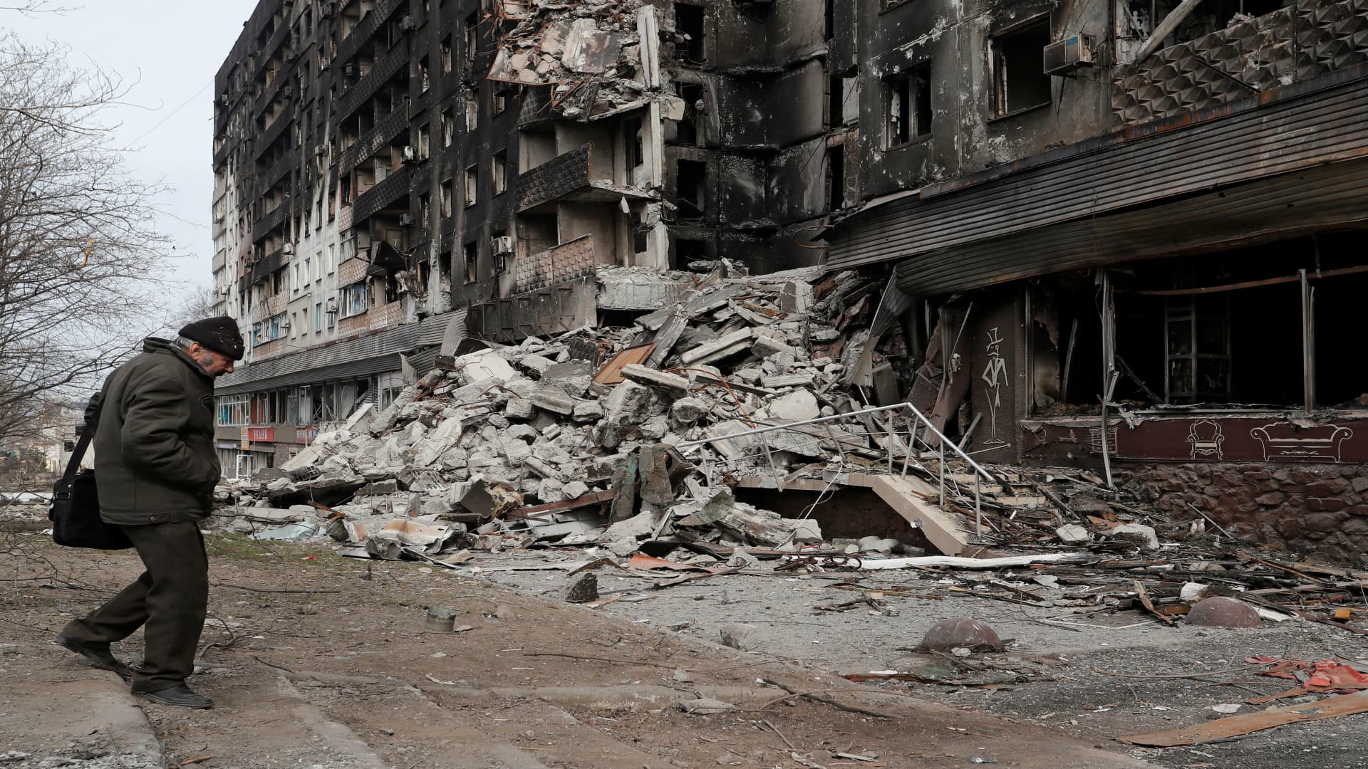 A local resident walks near an apartment building destroyed during Ukraine-Russia conflict in the besieged southern port city of Mariupol, Ukraine March 31, 2022. 