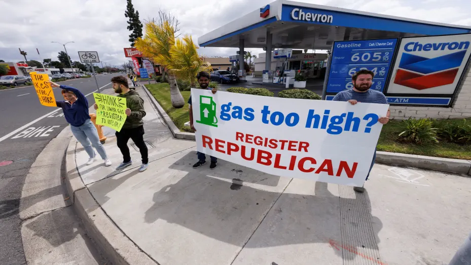 Republican activists seek drivers' attention as they work to register voters to their party at a gas station in Garden Grove, California, U.S., March 29, 2022. Picture taken March 29, 2022.   REUTERS/Mike Blake