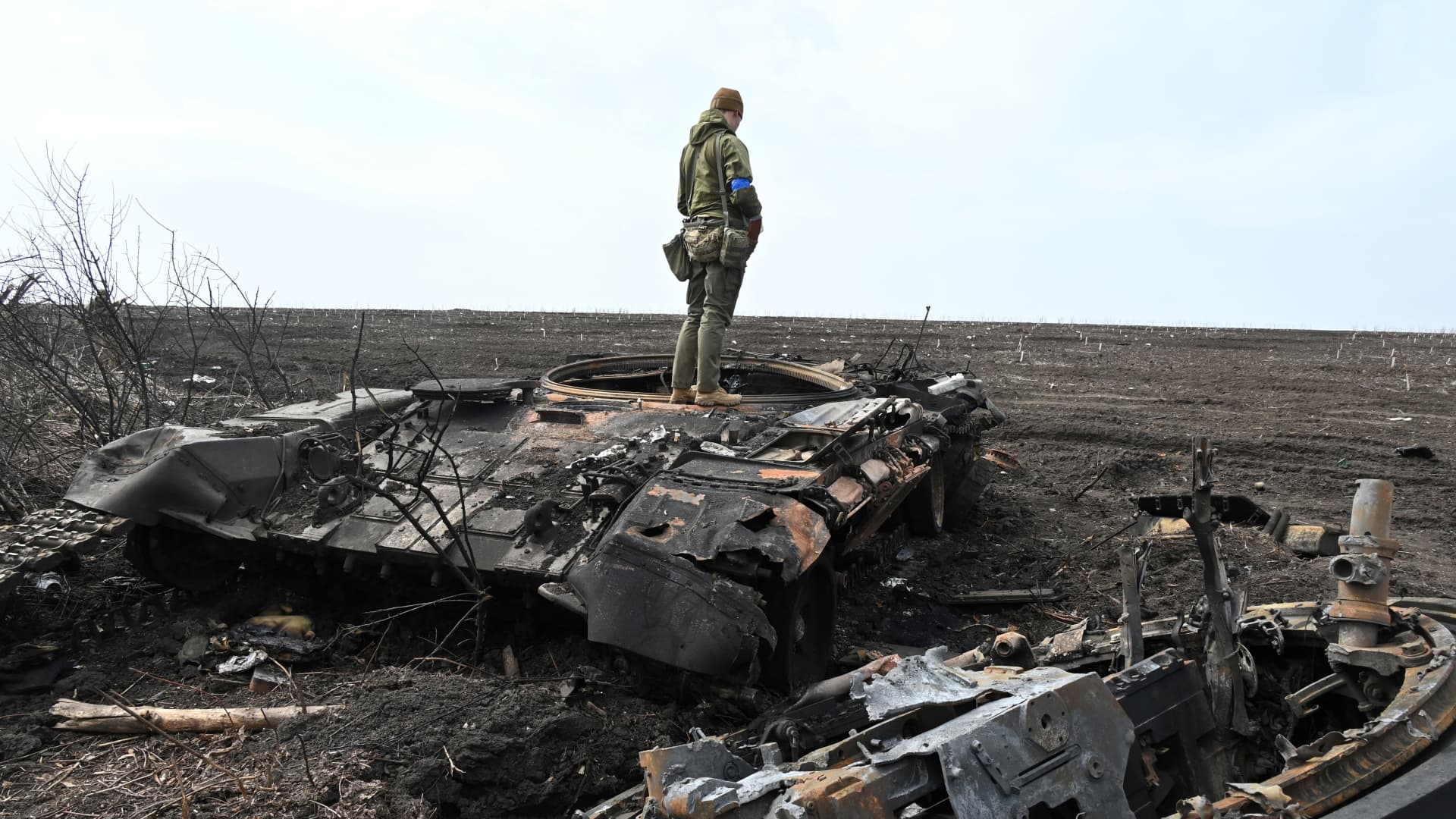 A Ukrainian soldier stands on the wreckage of a burnt Russian tank outside of the village of Mala Rogan, east of Kharkiv, on April 1, 2022.