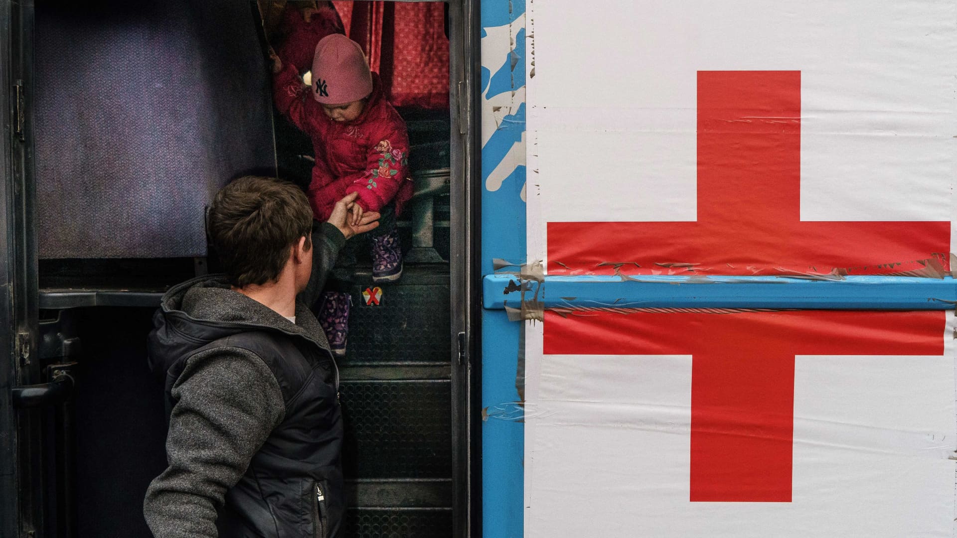 A child is helped off a bus by humanitarian workers at the registration center in Zaporizhzhia, Ukraine.
