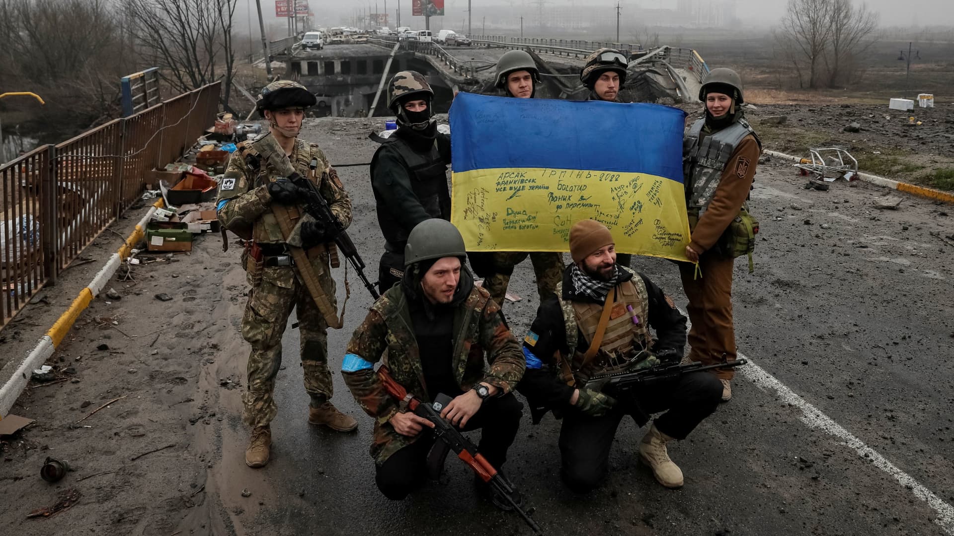 Ukrainian servicemen pose for a picture near a destroyed bridge as Russia's invasion of Ukraine continues, in the town of Irpin outside Kyiv April 1, 2022. 
