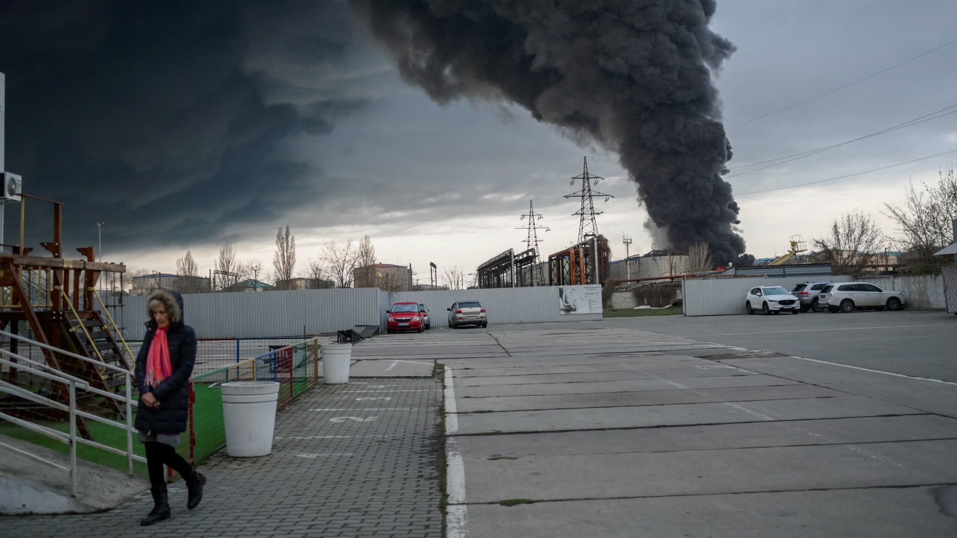 A woman seen walking in Ukraine's southern port city of Odesa as smoke fills the sky following a series of loud explosions.