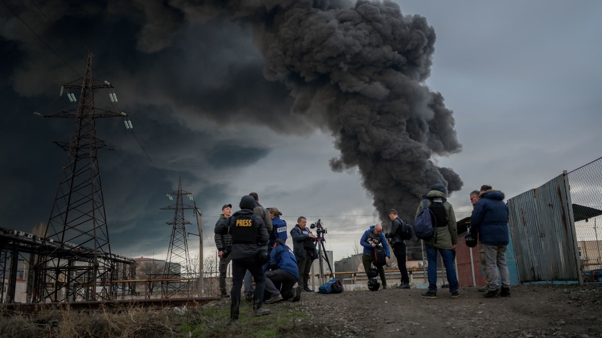 Journalists and residents look on as smoke fills the Odesa sky.