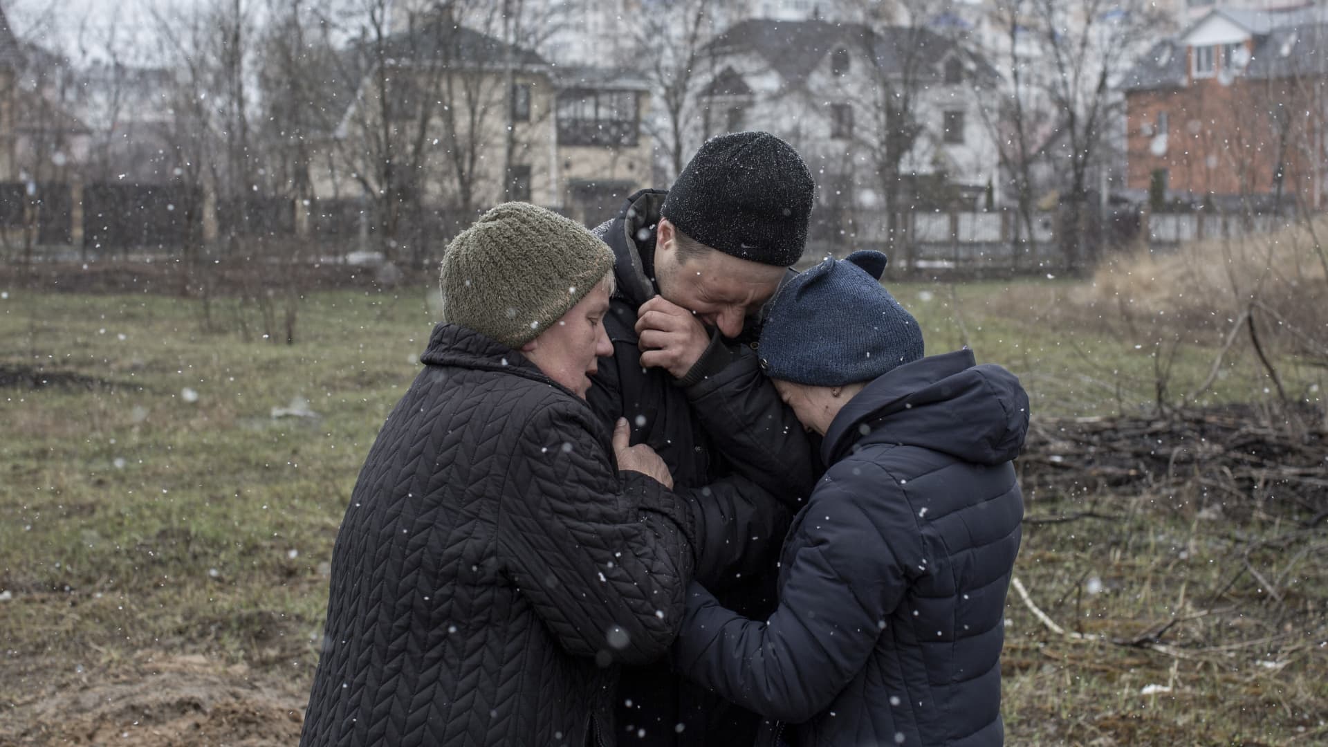 A family grieve for a missing relative in front of a mass grave in the town of Bucha, on the outskirts of Kyiv, on April 3, 2022.