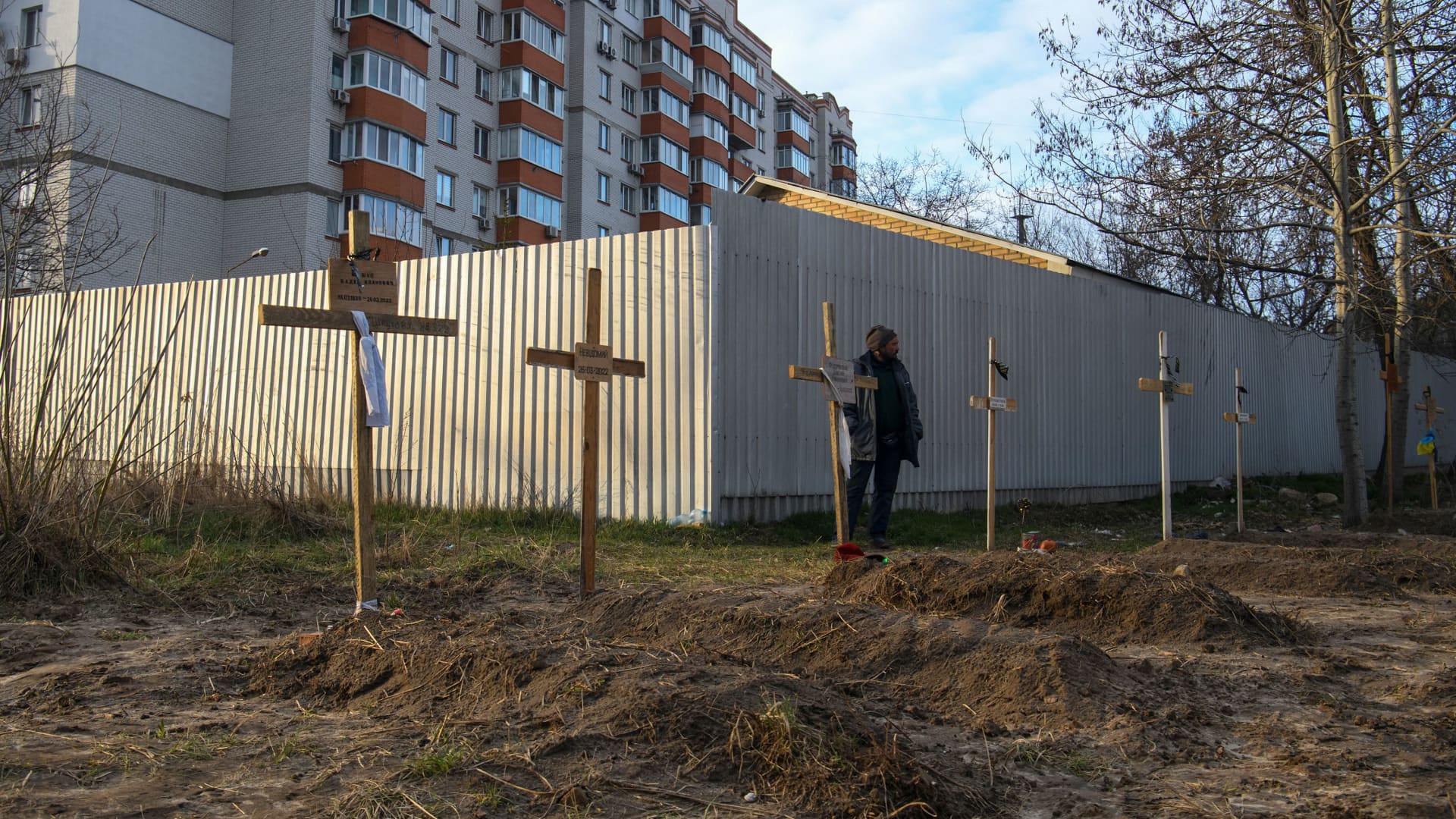A man stands next to graves with bodies of civilians, who according to local residents were killed by Russian soldiers, as Russia's attack on Ukraine continues, in Bucha, in Kyiv region, Ukraine April 4, 2022.