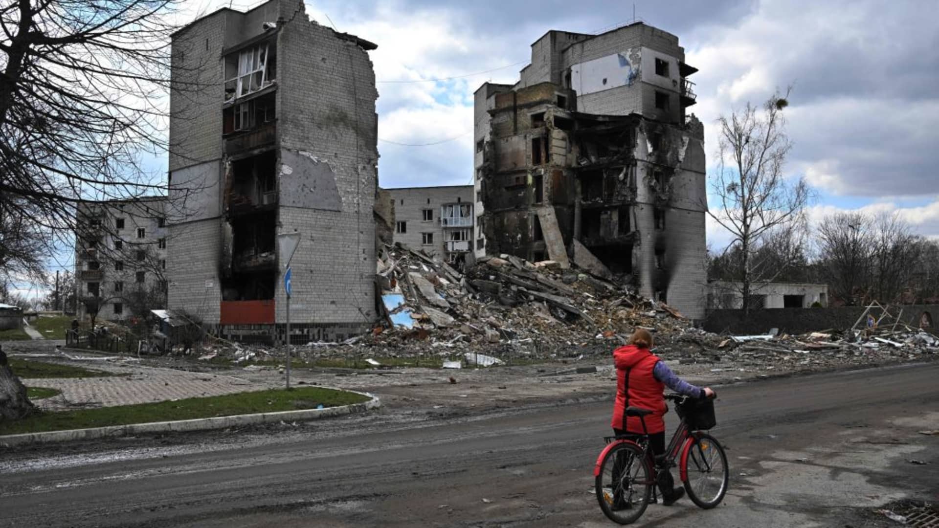 A woman pushes her bicycle past destroyed buildings in the town of Borodyanka on April 4, 2022.