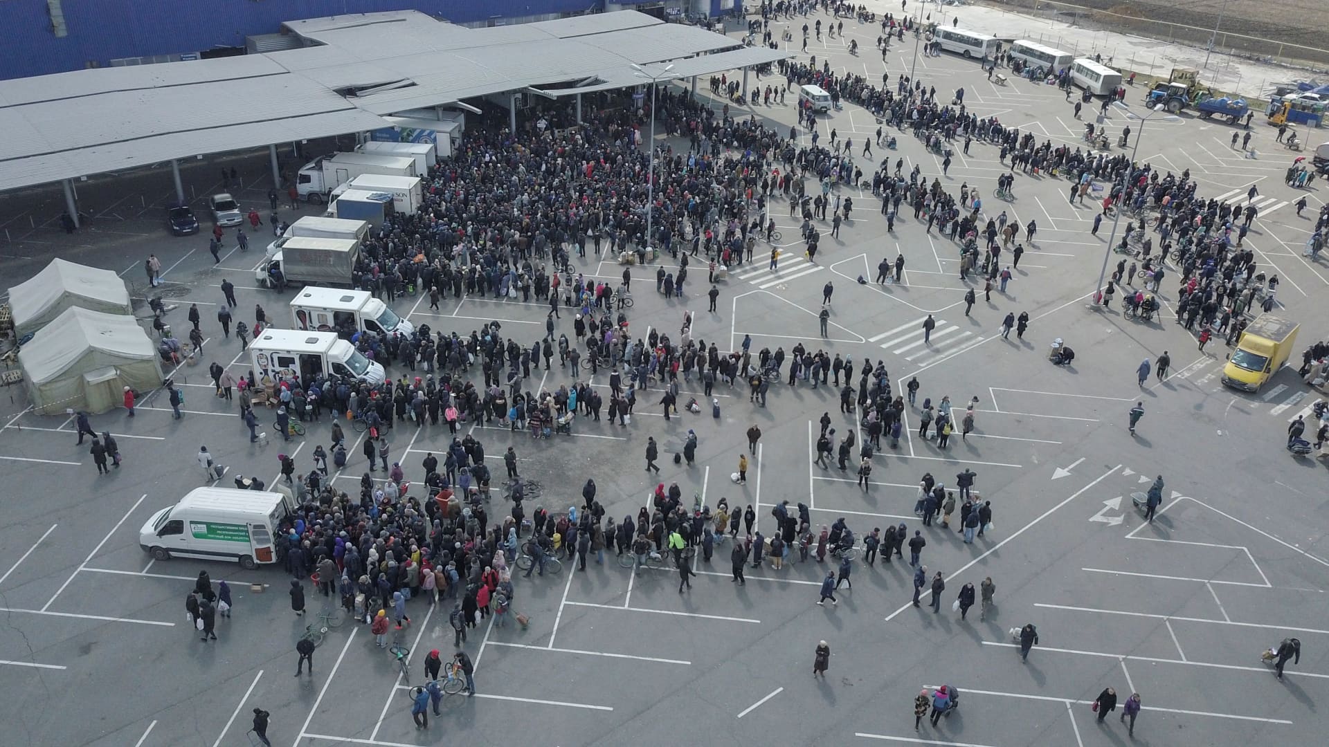 People gather near a damaged store of wholesaler Metro during the distribution of humanitarian aid in the course of Ukraine-Russia conflict in the southern port city of Mariupol, Ukraine April 5, 2022. Picture taken with a drone. 