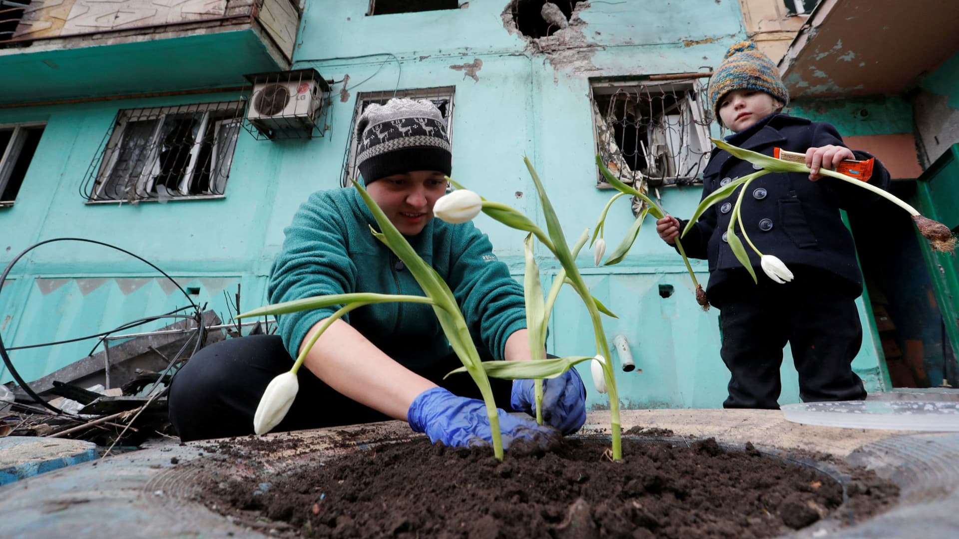 Local resident Viktoria Mukhina, 33, plants tulips with her daughter Miroslava near an apartment building damaged during Ukraine-Russia conflict in the southern port city of Mariupol, Ukraine April 4, 2022.