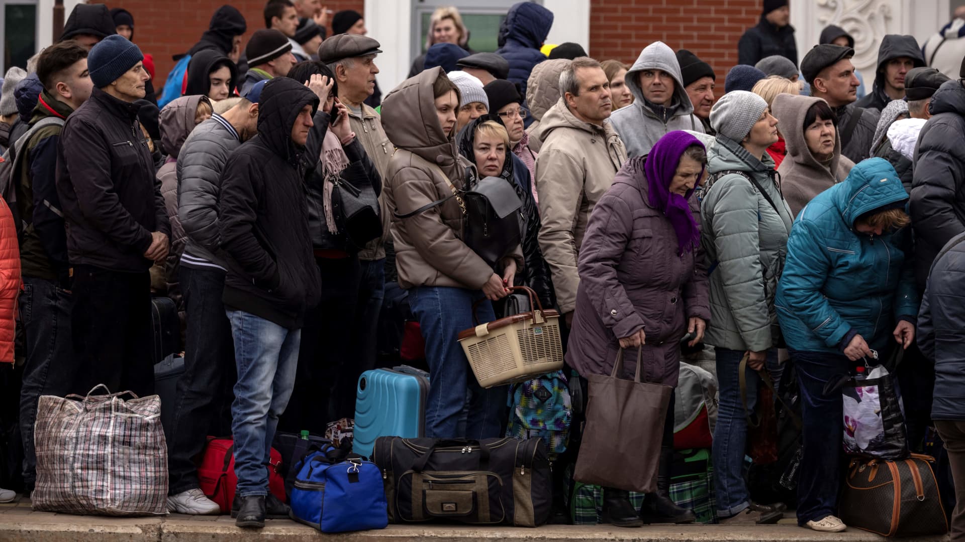 Families hold bags as they wait to board a train at Kramatorsk central station as they flee the eastern city of Kramatorsk, in the Donbass region on April 5, 2022.