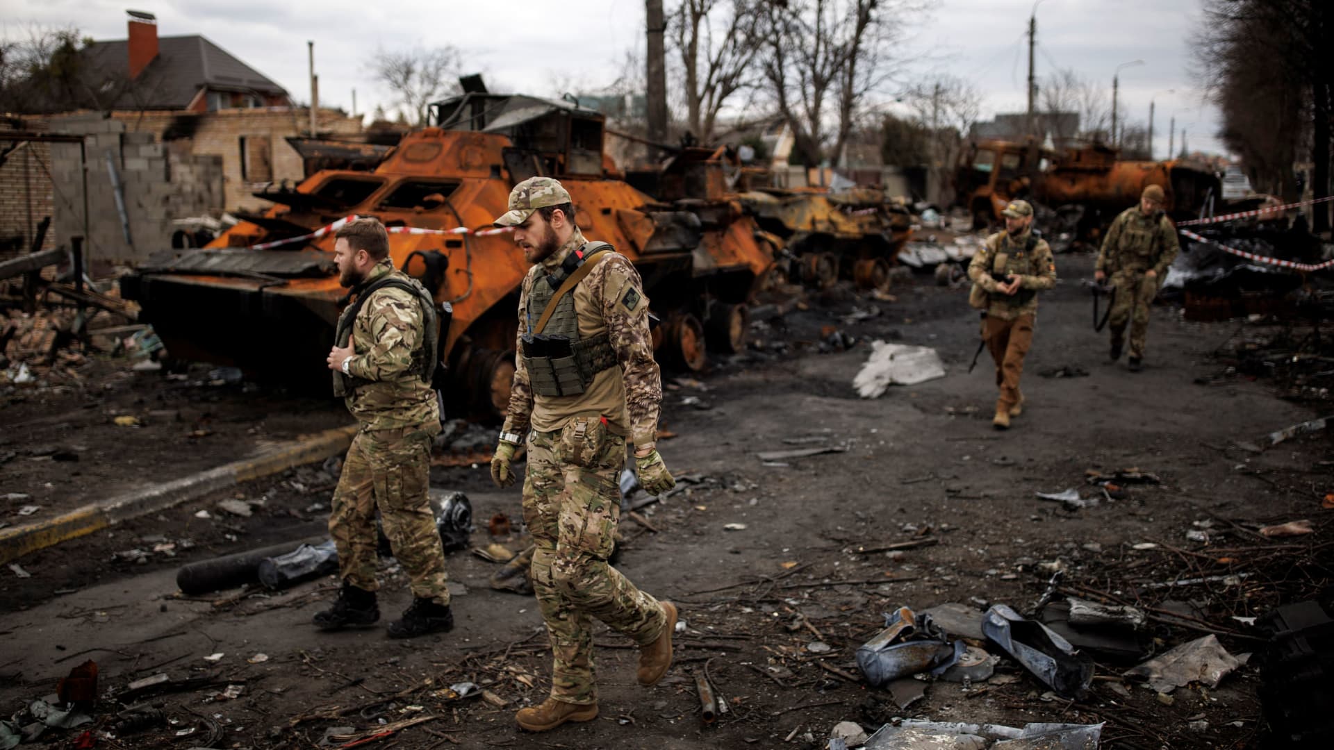 Ukrainian soldiers walk next to destroyed Russian tanks and armored vehicles, amid Russia's invasion of Ukraine, in Bucha, in Kyiv region, Ukraine, April 6, 2022.