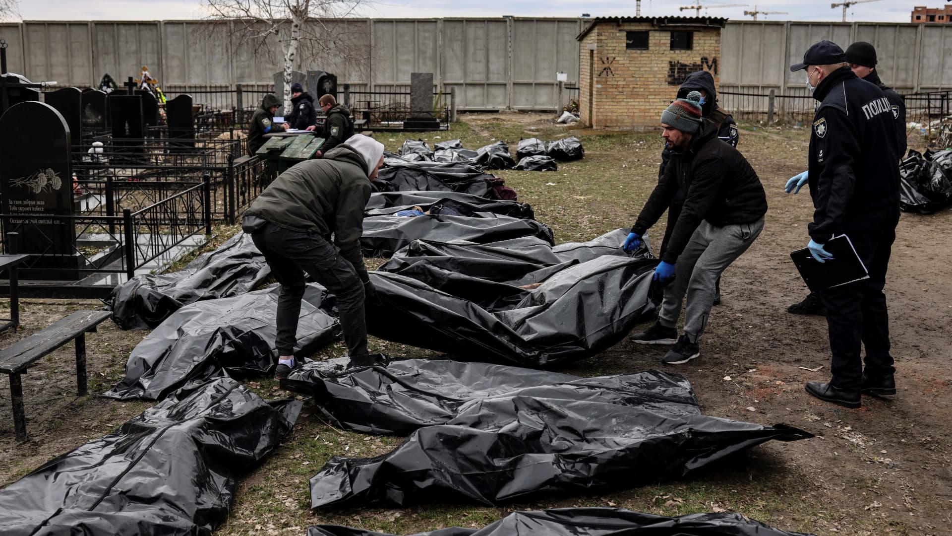 EDITORS NOTE: Graphic content / Workers line up bodies for identification by forensic personnel and police officers in the cemetery in Bucha, north of Kyiv, on April 6, 2022, after hundreds of civilians were found dead in areas from which Russian troops have withdrawn around Ukraine's capital, including the town of Bucha.