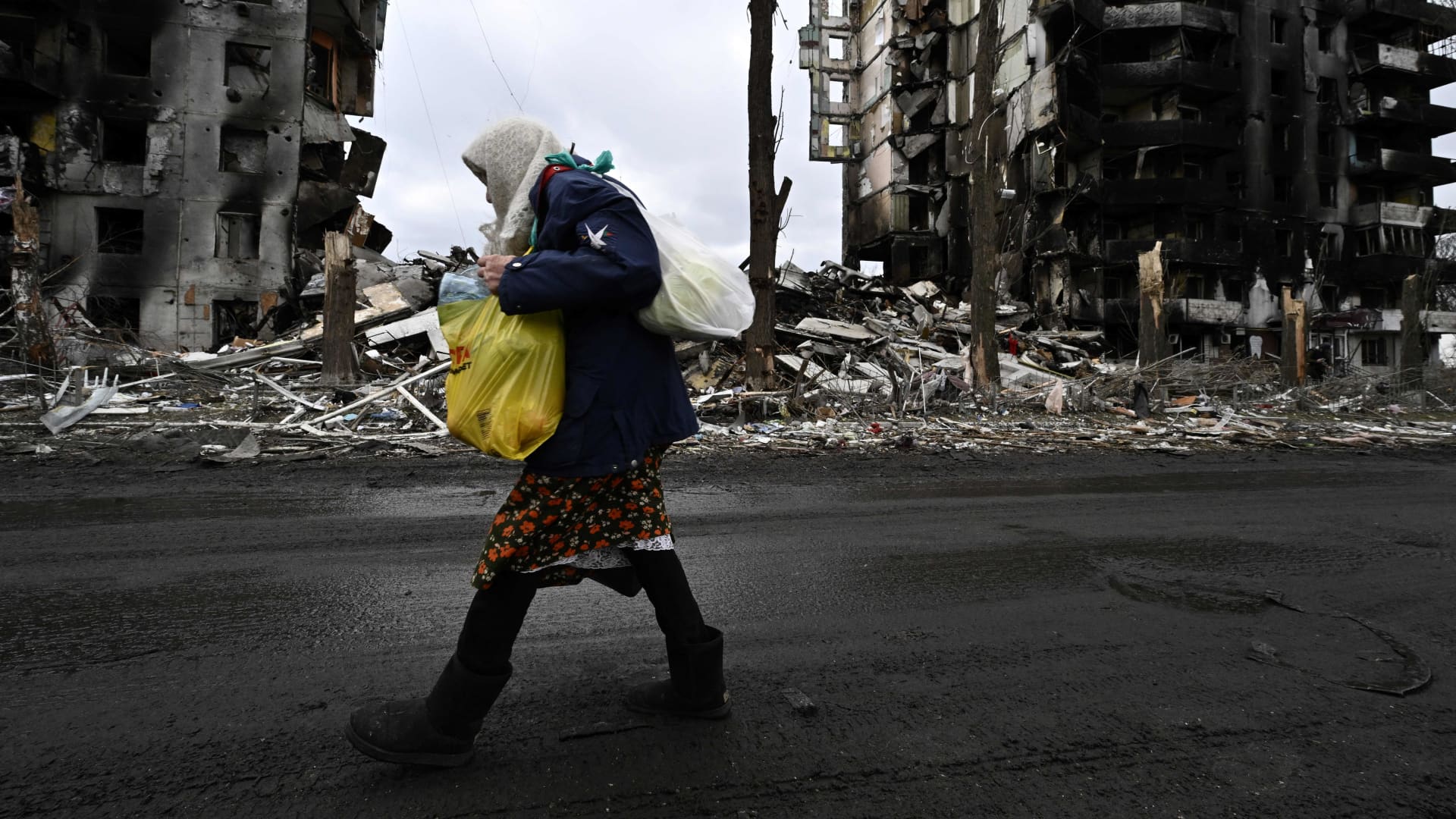 An woman walks in front of destroyed buildings in the town of Borodianka on April 6, 2022, where the Russian retreat last week has left clues of the battle waged to keep a grip on the town, just 50 kilometres (30 miles) north-west of the Ukrainian capital Kyiv.