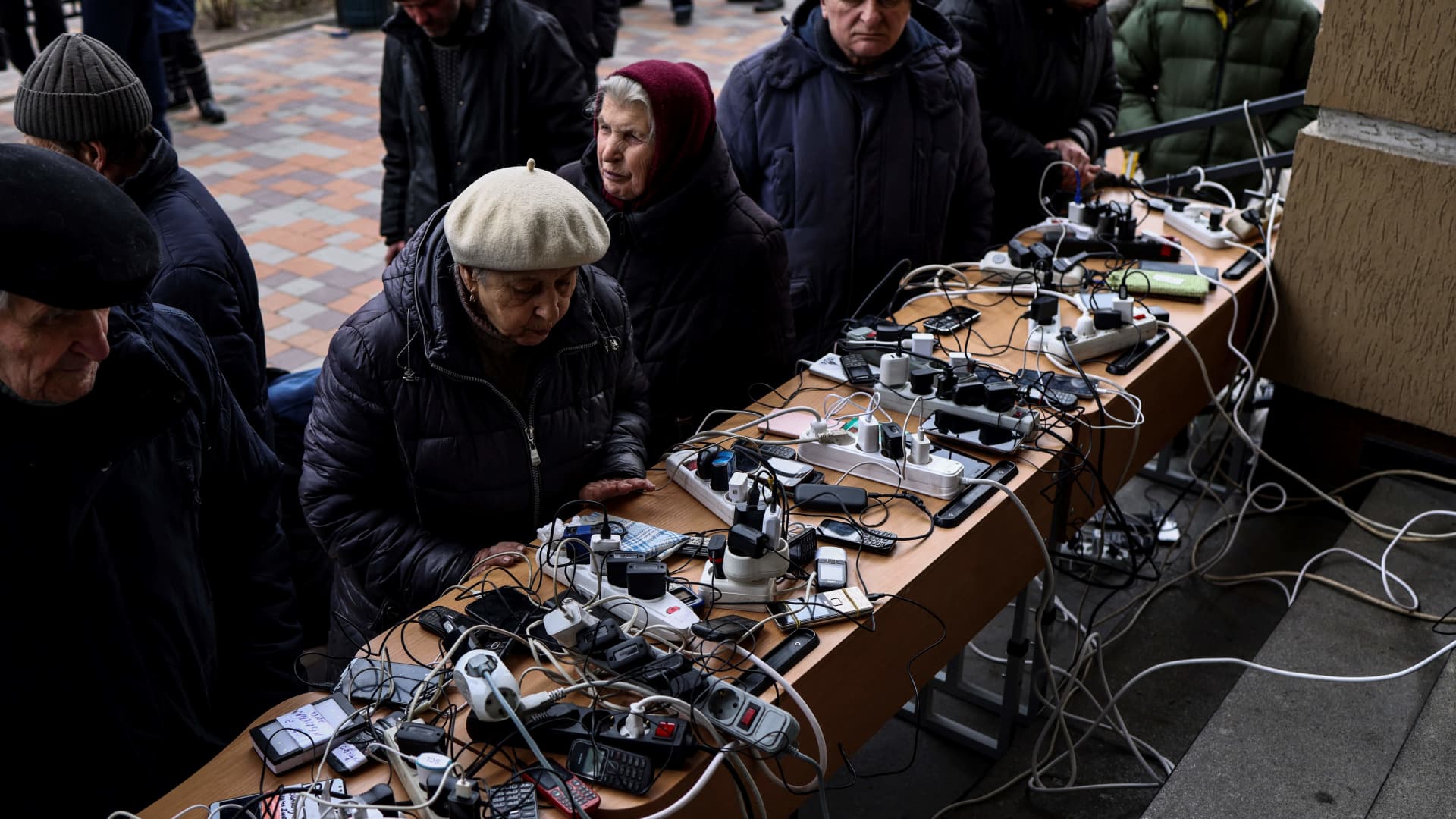 People charge their cellphones in a public building in Bucha, northwest of Kyiv, on April 6, 2022, during Russia's military invasion launched on Ukraine.