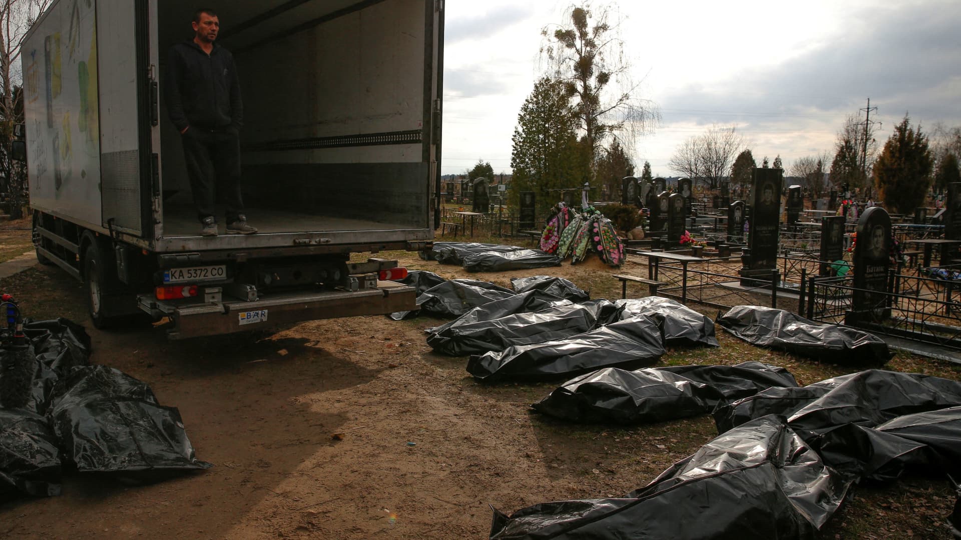 A funeral service employee looks at bodies of civilians, collected from streets to local cemetery, as Russia's attack on Ukraine continues, in the town of Bucha, outside Kyiv, Ukraine April 6, 2022.