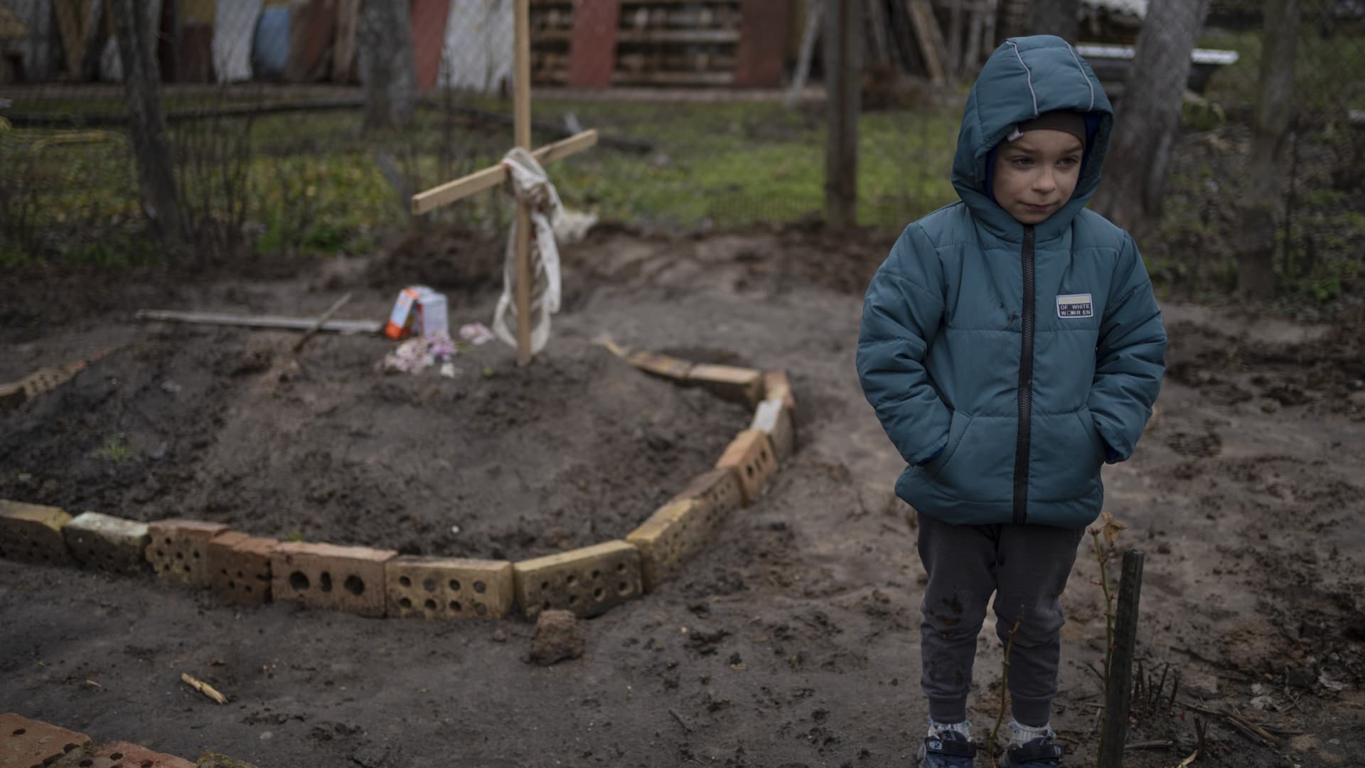 In the courtyard of their house, Vlad Tanyuk, 6, stands near the grave of his mother Ira Tanyuk, who died because of starvation and stress due to the war, on the outskirts of Kyiv, Ukraine, Monday, April 4, 2022.