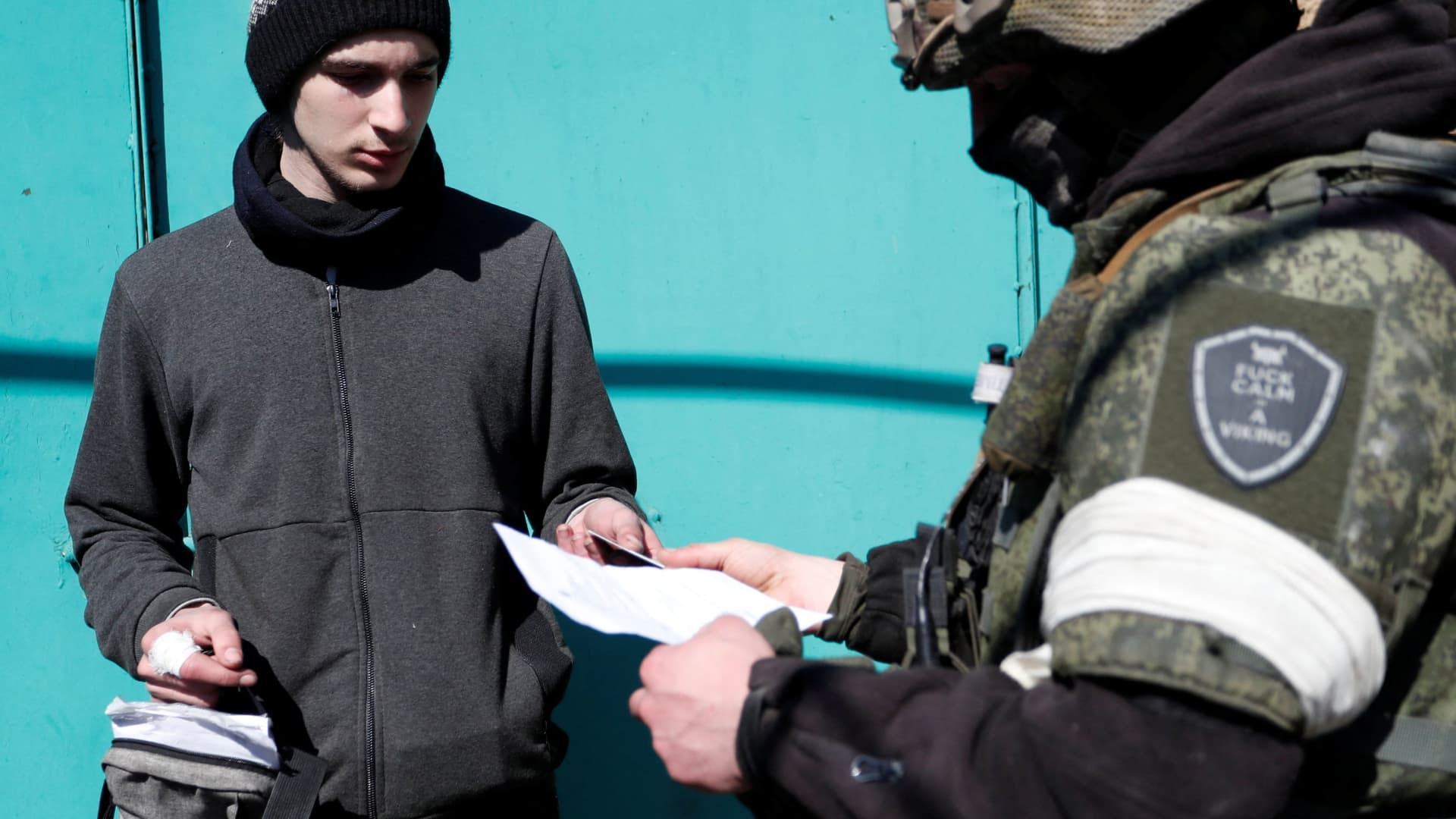 A service member of pro-Russian troops checks the documents of a local resident during Ukraine-Russia conflict in the southern port city of Mariupol, Ukraine April 7, 2022.